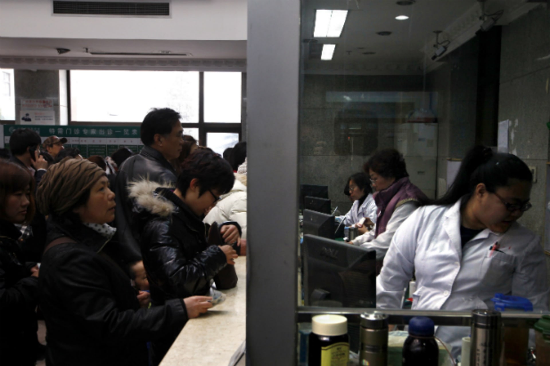 People wait in line at a counter for medical services at the Guanganmen Chinese medicine hospital for treatment in Beijing.