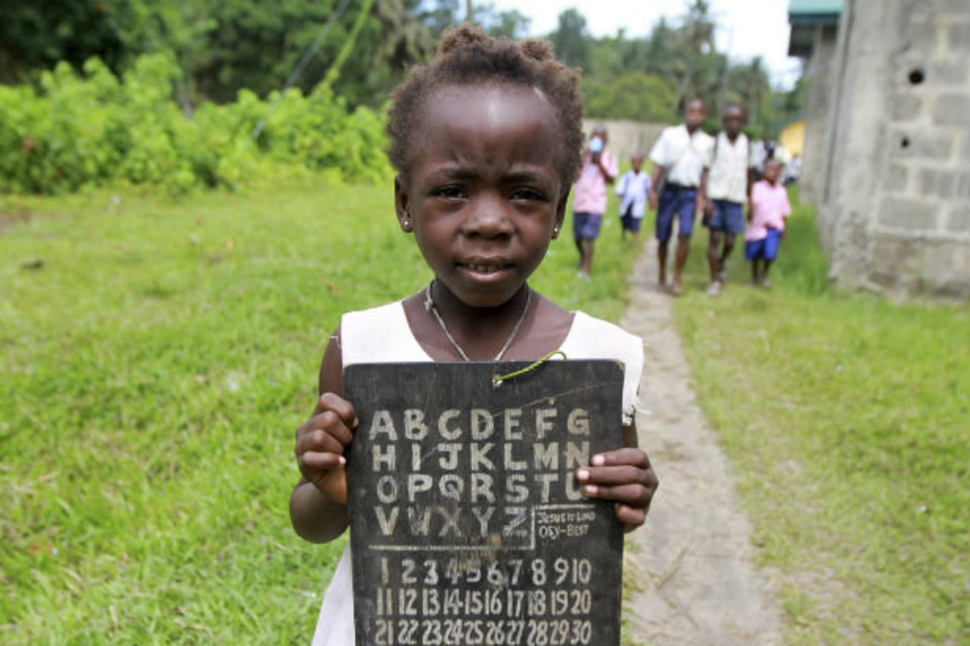 A girl holds a slate with alphabets and numbers along a path in the Koluama village in Nigeria's Bayelsa state May 15, 2012.