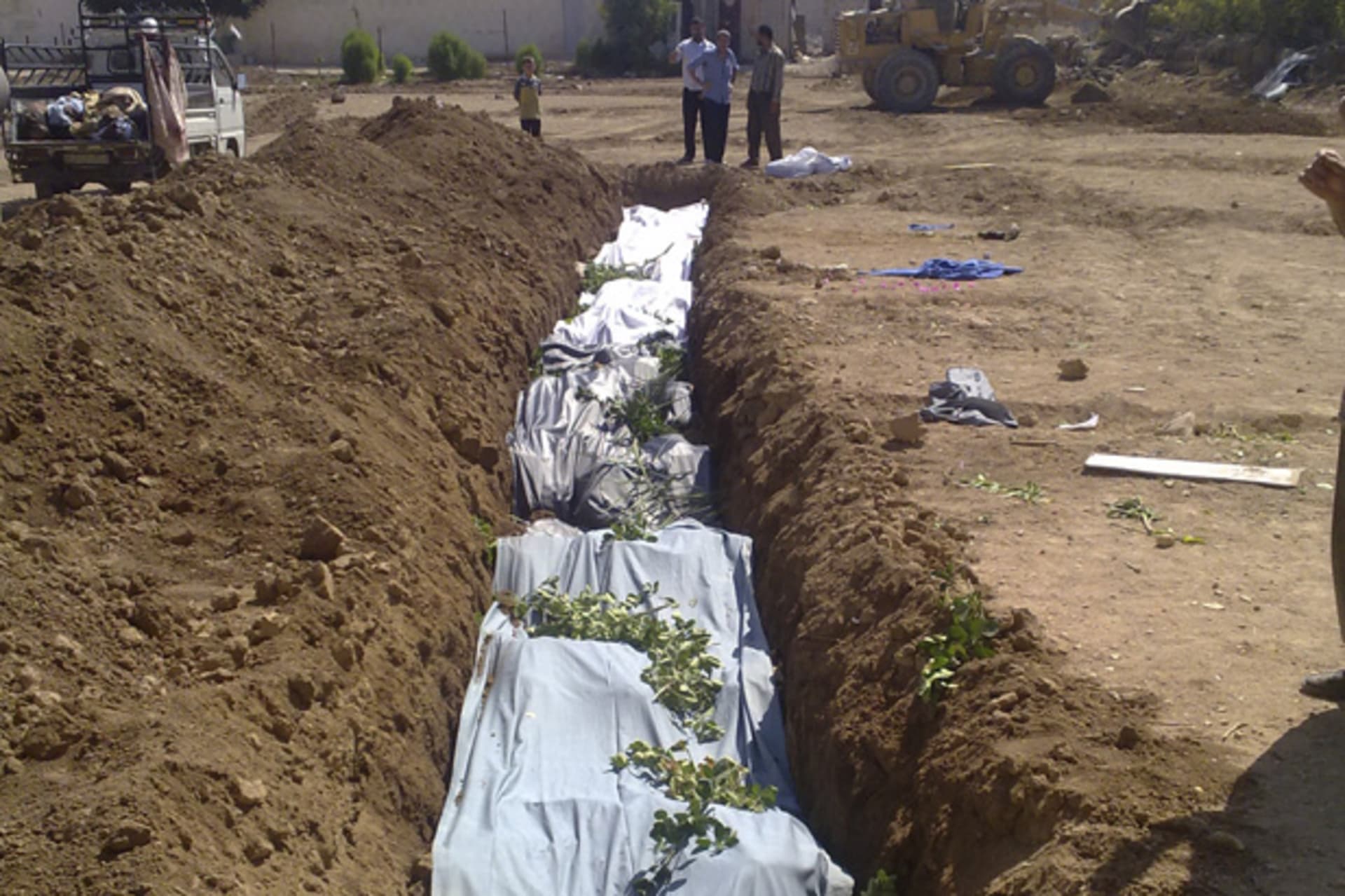 In this handout photo provided by the Shaam News Network, a mass burial for the victims whom activists said were killed by forces loyal to Syria's President Bashar Al-Assad is seen in Daraya near Damascus