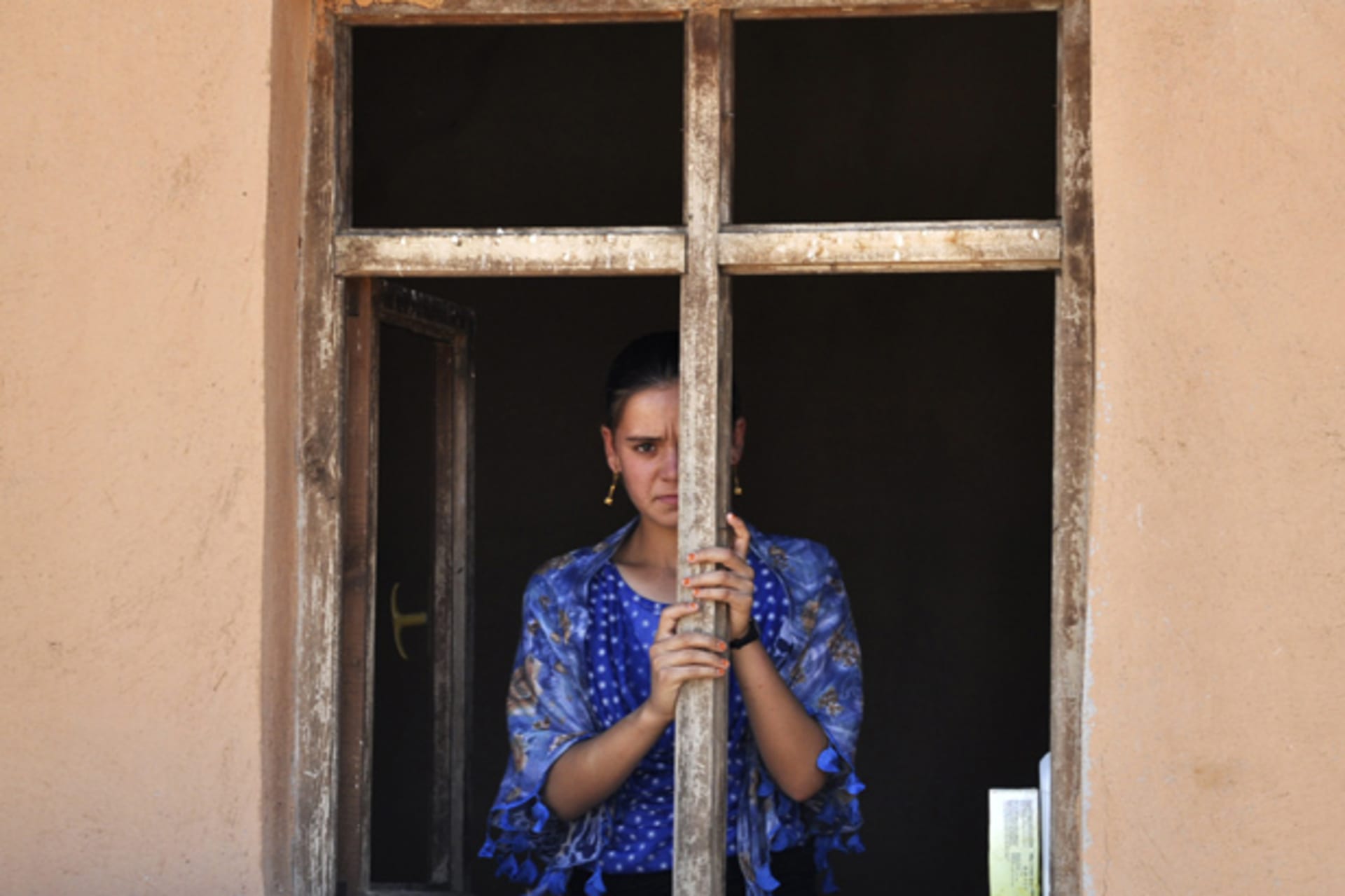 A displaced woman from the minority Yazidi sect, fleeing violence in Iraq, looks out from an abandoned house where she is taking refuge in the southeastern Turkish town of Silopi