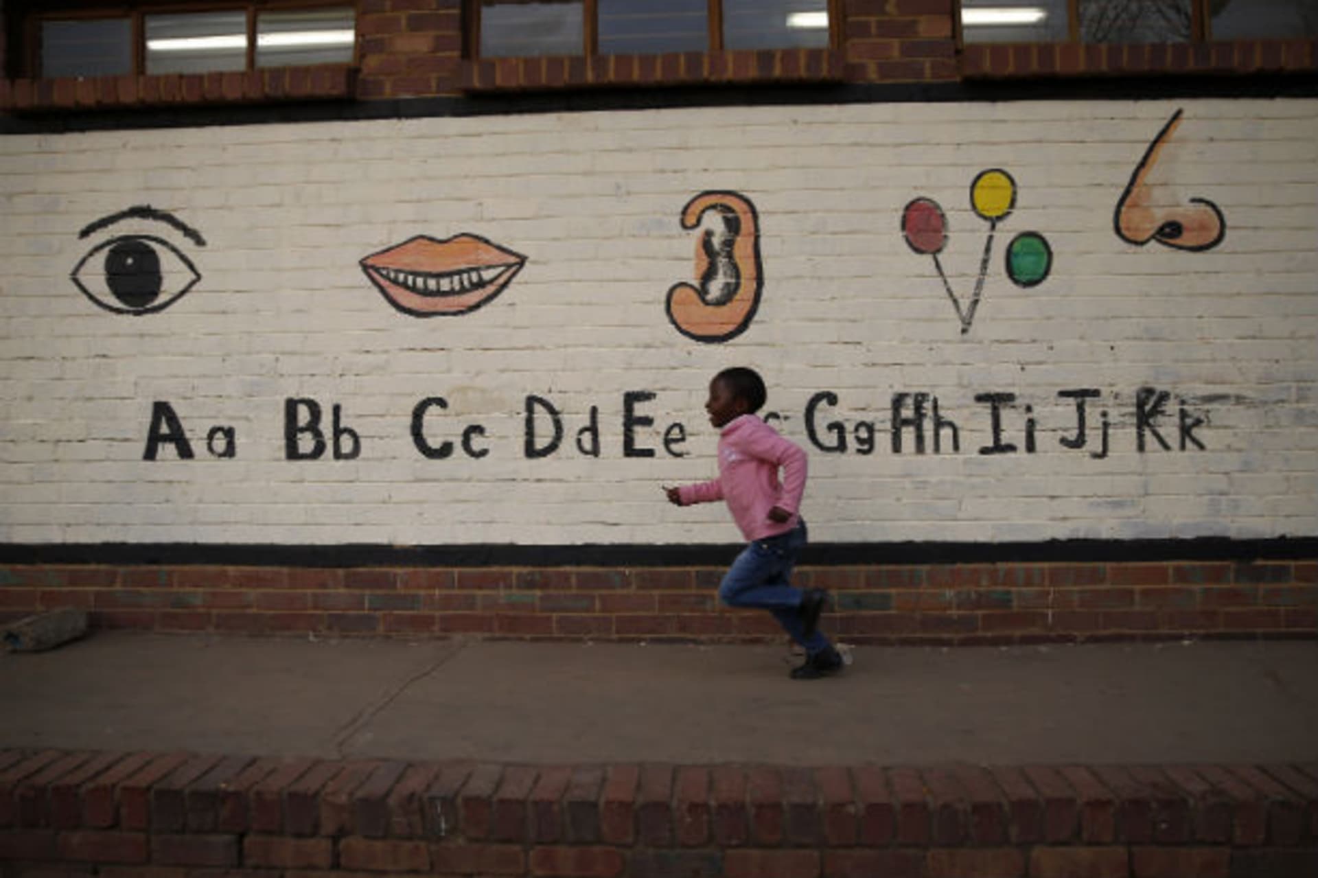 A child runs past a mural at a township school as the school prepares to wish former President Nelson Mandela happy birthday in Atteridgeville near Pretoria, July 18, 2013.