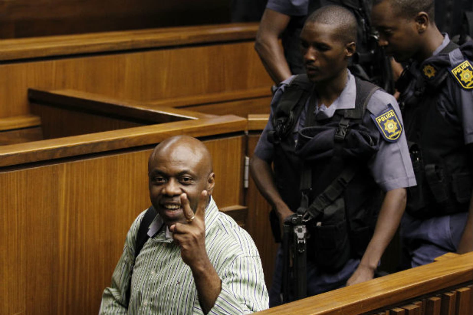 Nigerian militant leader Henry Okah (L) gestures as he is escorted by police after his sentencing was postponed at a Johannesburg court February 28, 2013.