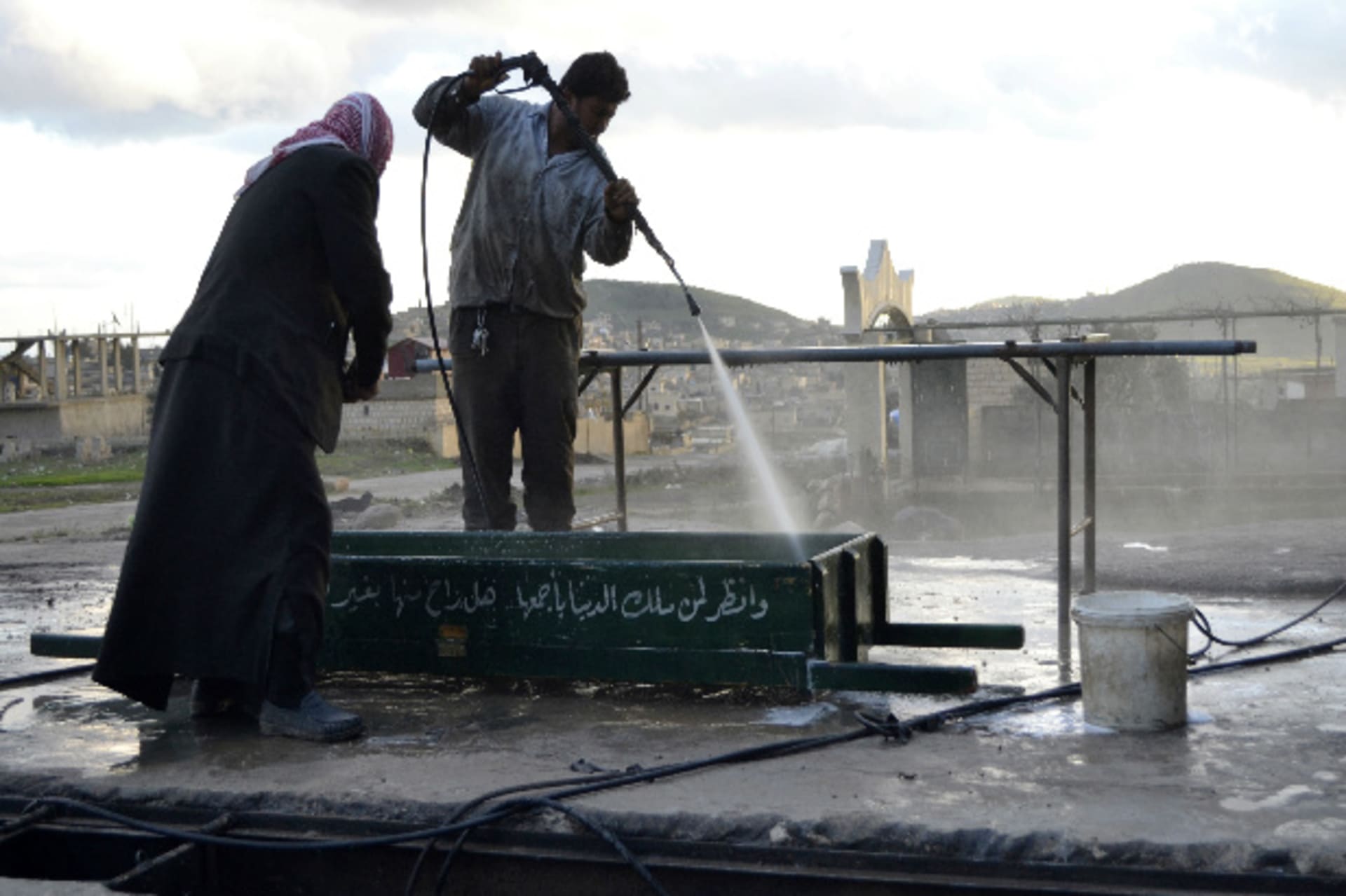 Men wash blood off a coffin along a street in Jabal al-Zawiya in the southern countryside of Idlib January 4, 2015. Picture taken January 4, 2015. Stringer/Reuters