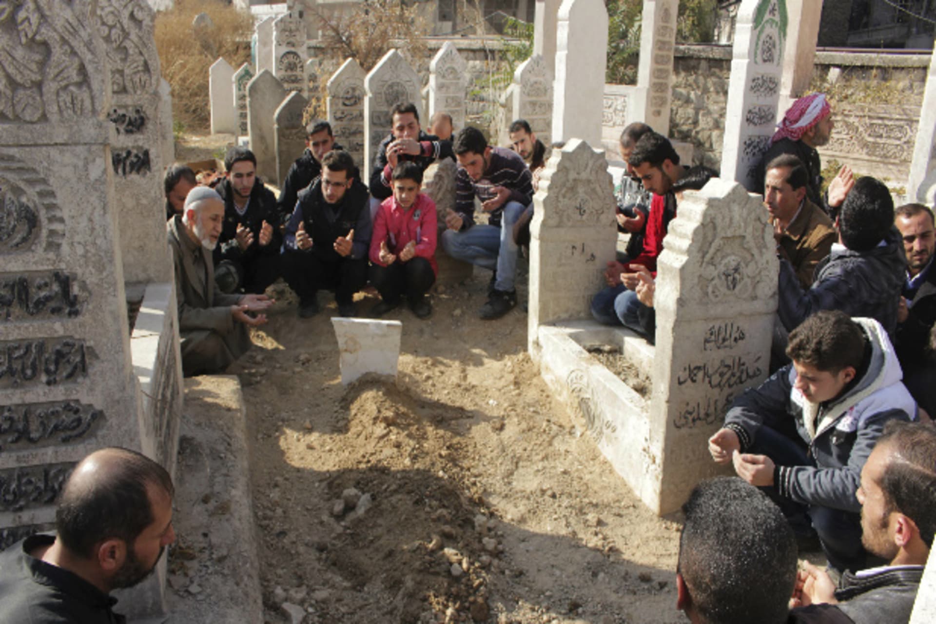 Family and friends of a Free Syrian Army fighter attend his funeral, after he died in clashes with forces loyal to President Bashar al-Assad, in a graveyard in Aleppo's Karm al-Jabal district November 23, 2013 (Barakat/Courtesy Reuters).