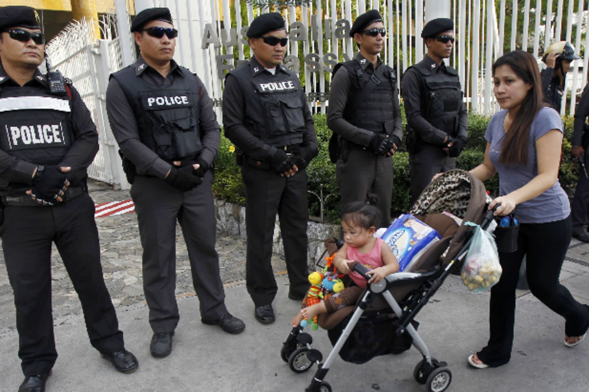 <p>A woman and her child walks past policemen standing guard as anti-coup protesters gather outside the Australian embassy in Bangkok on June 4, 2014 (Chaiwat Subprasom/Courtesy Reuters).</p>
