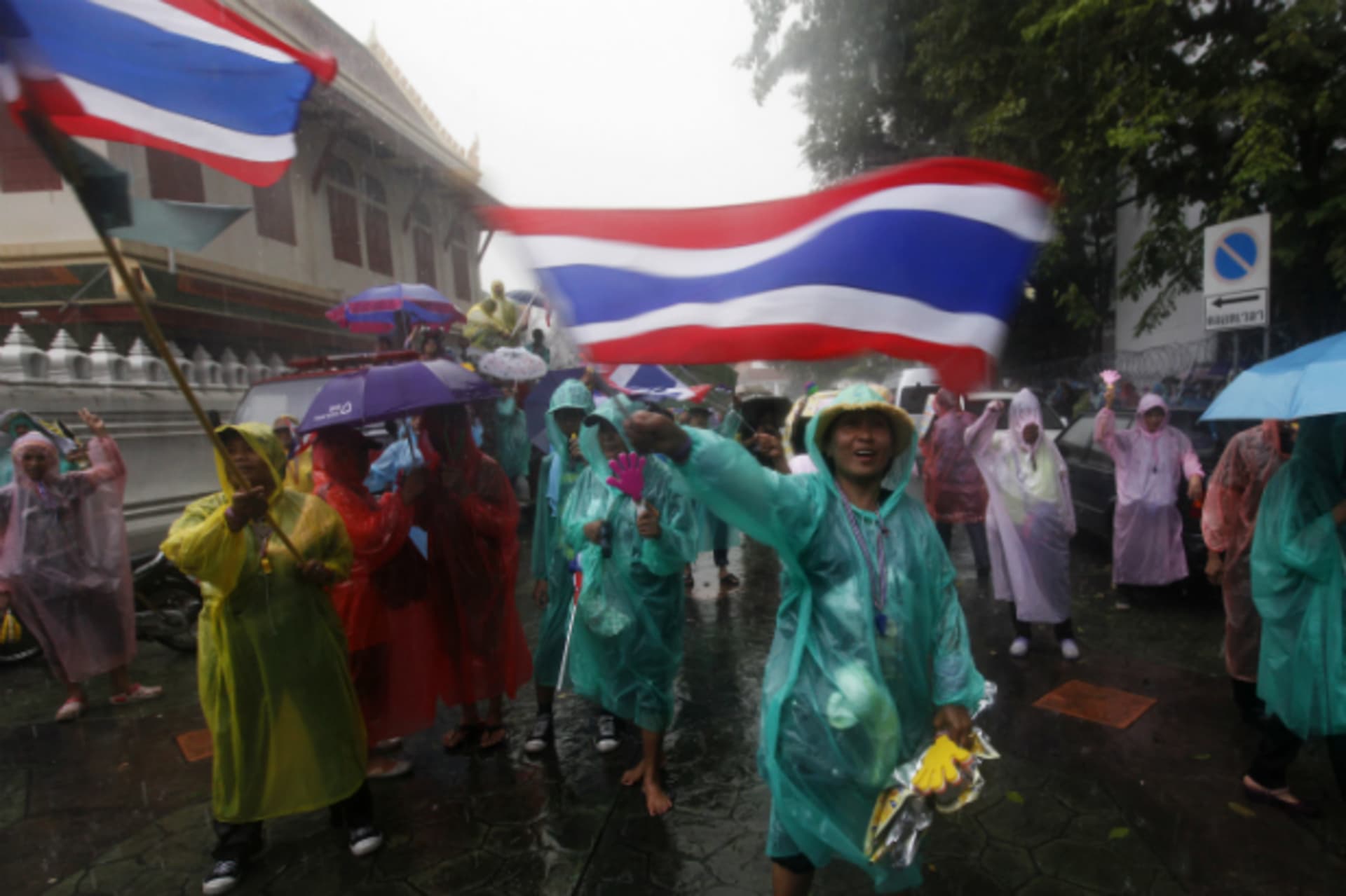 <p>Anti-government protesters wave flags while standing in heavy rain outside the Interior Ministry in Bangkok on November 26, 20…nd’s Interior Ministry on Tuesday, a day after they stormed compounds of two other ministries. (Kerek Wongsa/Courtesy Reuters)</p>

