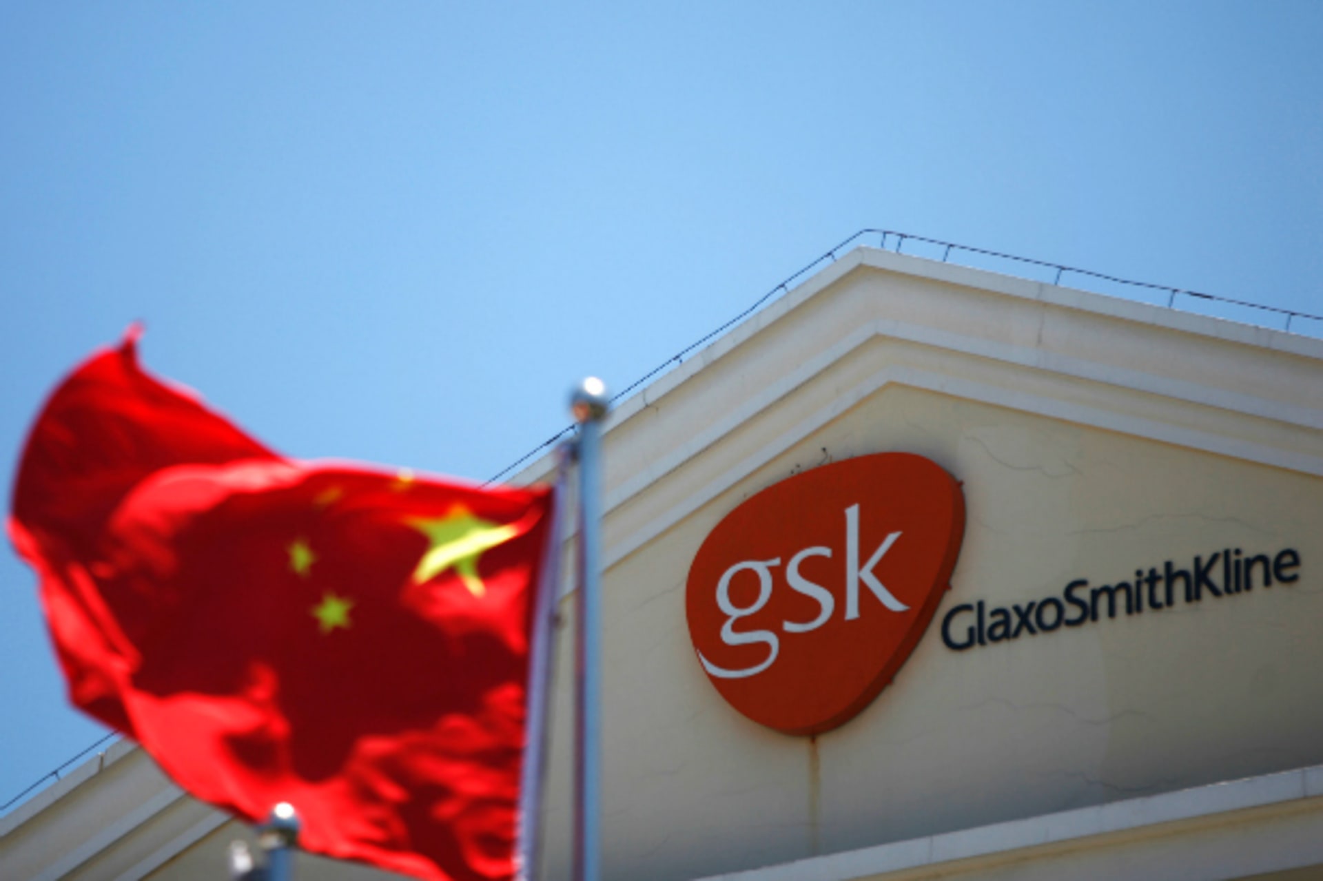 A Chinese national flag flutters  in front of  a GlaxoSmithKline (GSK) office building in Shanghai on July 12, 2013.