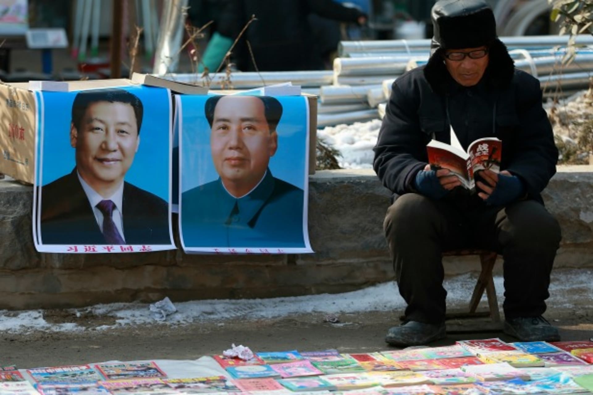 <p>A book vendor reads a book as he waits for customer next to portraits of Chinese President Xi Jinping (L) and late Chairman Ma…vince January 30, 2015. REUTERS/Stringer (CHINA – Tags: SOCIETY POLITICS) CHINA OUT. NO COMMERCIAL OR EDITORIAL SALES IN CHINA</p>
