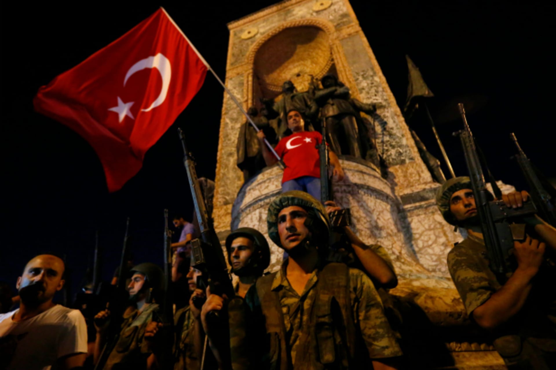 <p>Turkish military stand guard near the the Taksim Square as peiple wave with Turkish flags in Istanbul, Turkey (Murad Sezer/Reuters).</p>