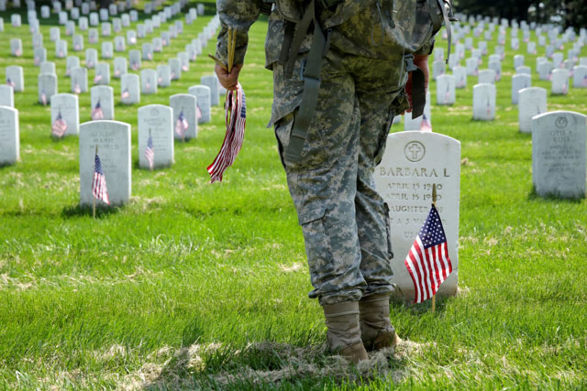 <p>A soldier places flags in front of the graves at Arlington National Cemetery in Washington, DC. (Joshua Roberts/Reuters)</p>
