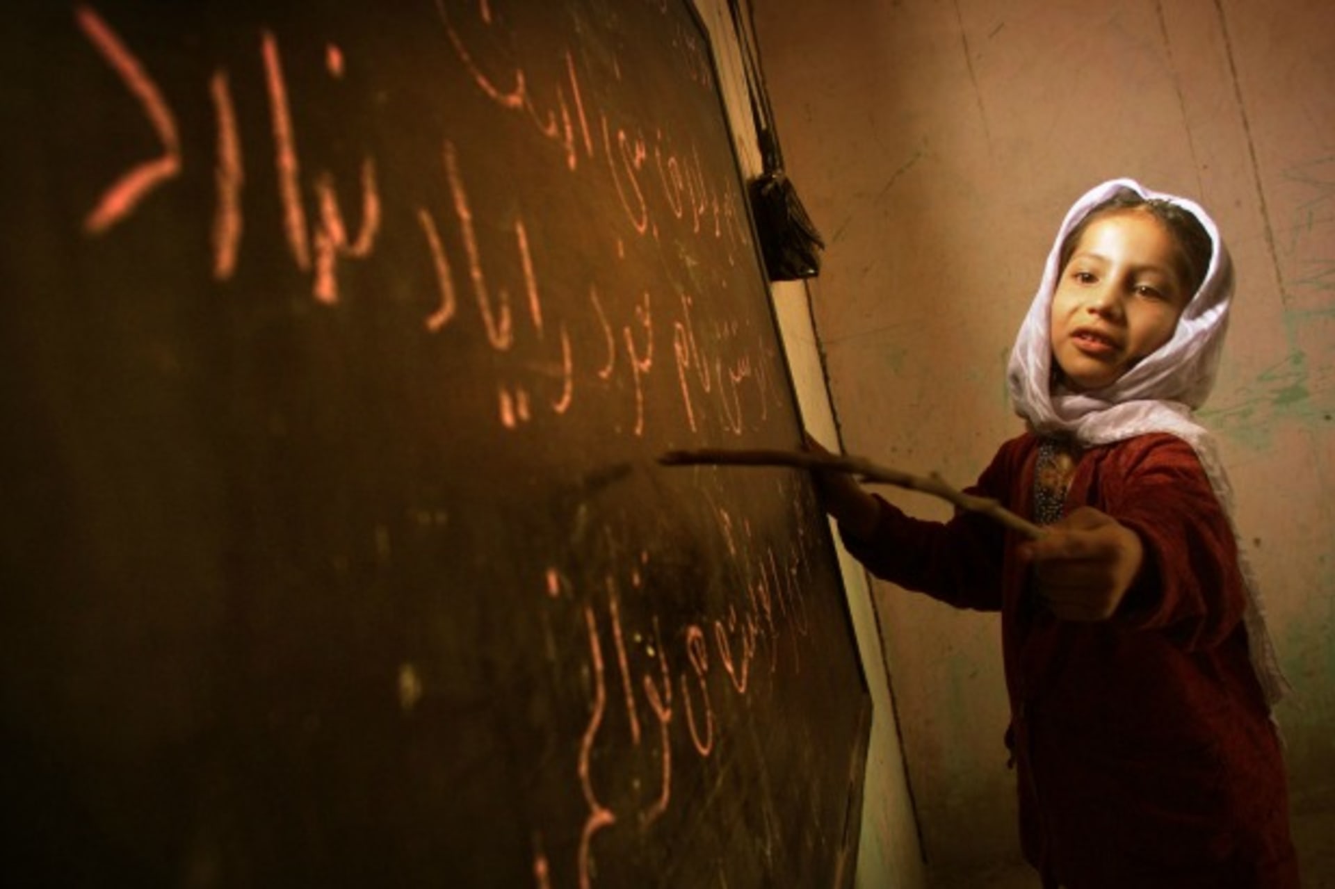 <p>A girl reads from the board in a home-based school in Kabul, Afghanistan, December 2001 (Courtsey Damir Sagolj/Reuters).</p>
