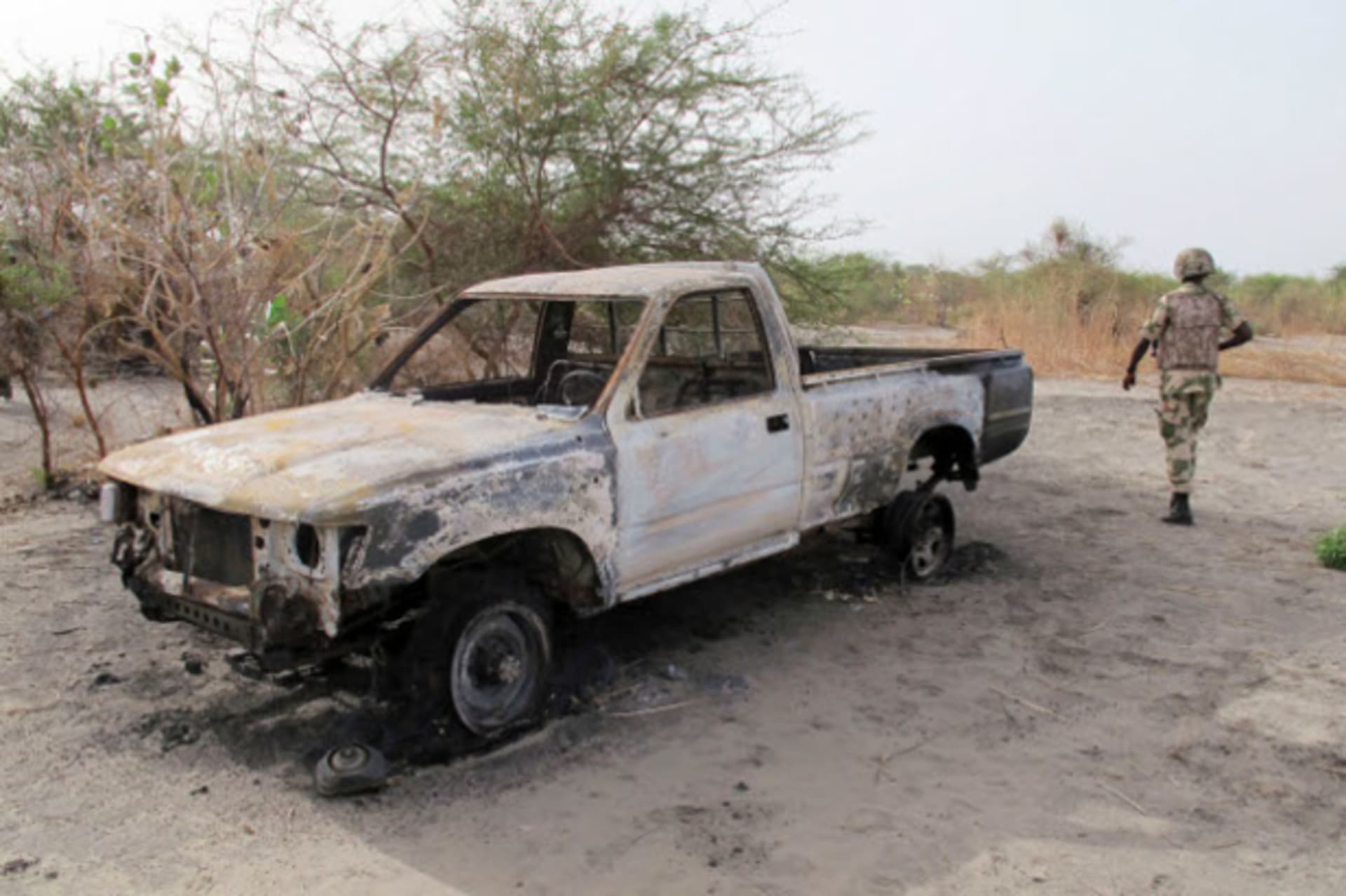 A soldier walks past a burnt vehicle during a military patrol in Hausari village, near Maiduguri June 5, 2013.