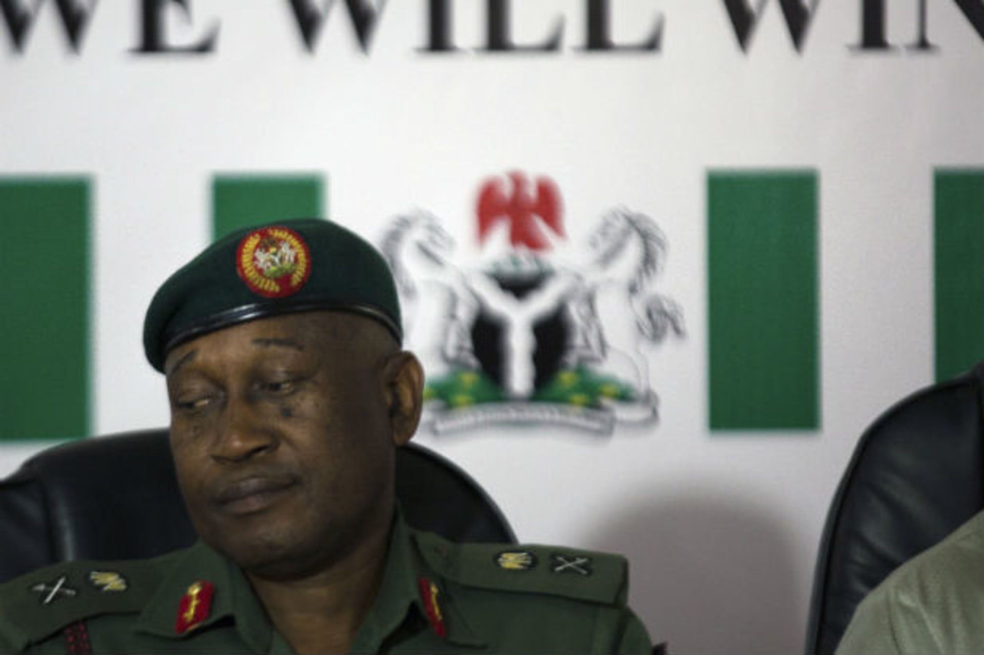 Nigerian army spokesman Major General Chris Olukolade sits in front of a poster reading "we will win" at a news conference in Abuja May 19, 2014.