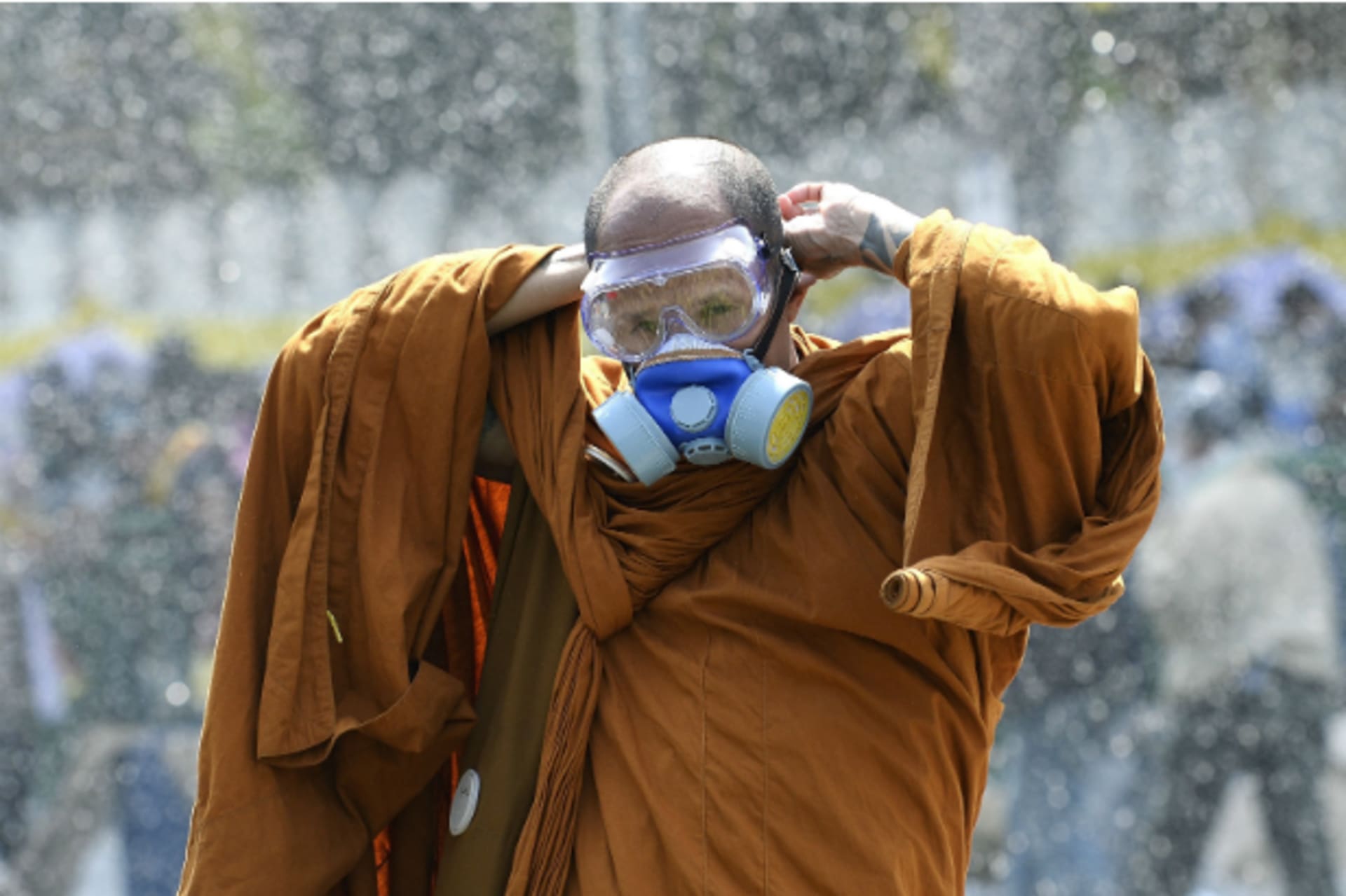 <p>A Thai Buddhist monk puts on a gas mask as riot police use water cannon and tear gas while anti-government protesters attempt to remove barricades outside Government House in Bangkok on December 2, 2013. (Dylan Martinez/Courtesy Reuters)</p>
