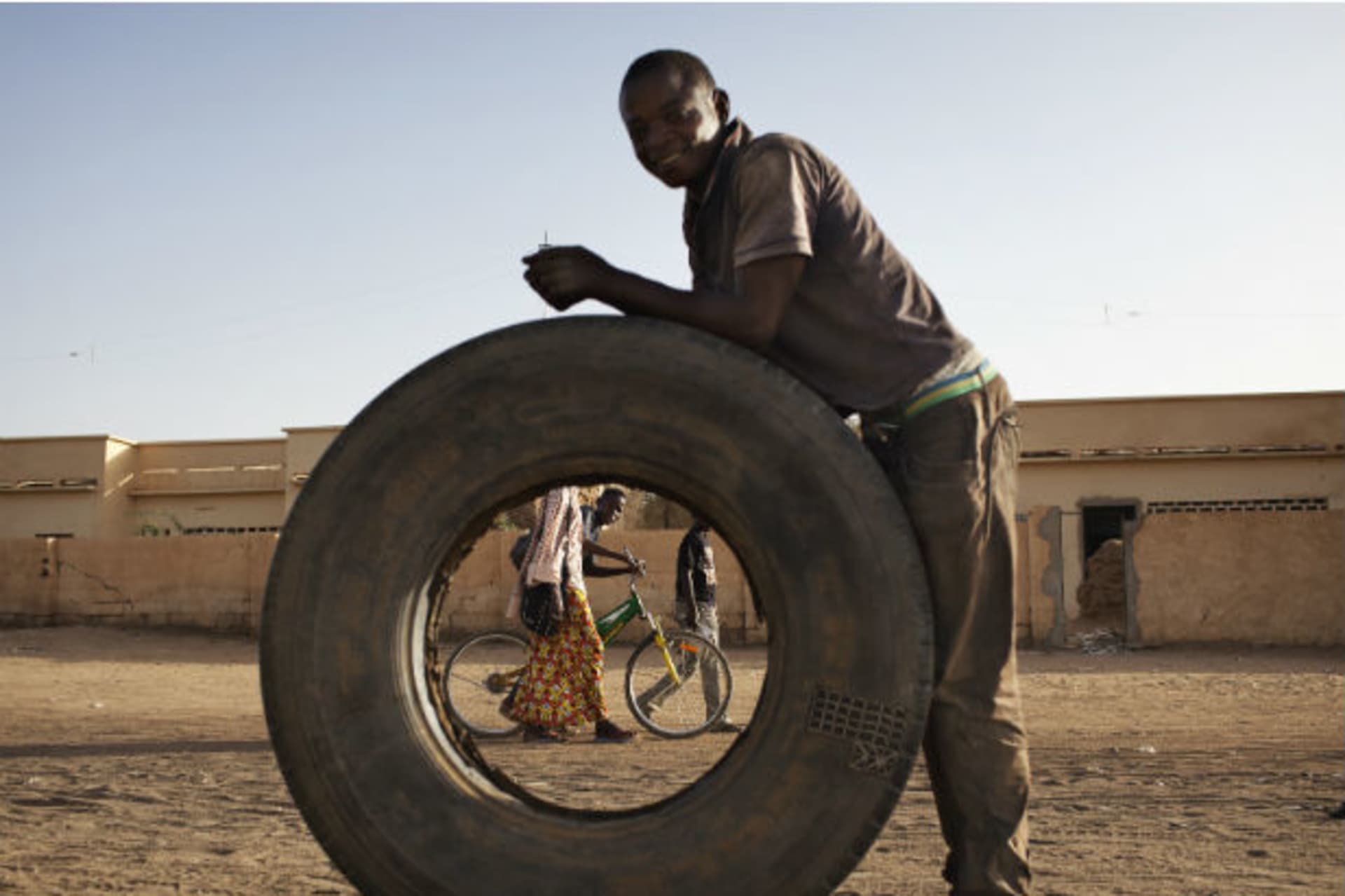 People walking down the street are seen through a large tyre in Gao March 12, 2013.