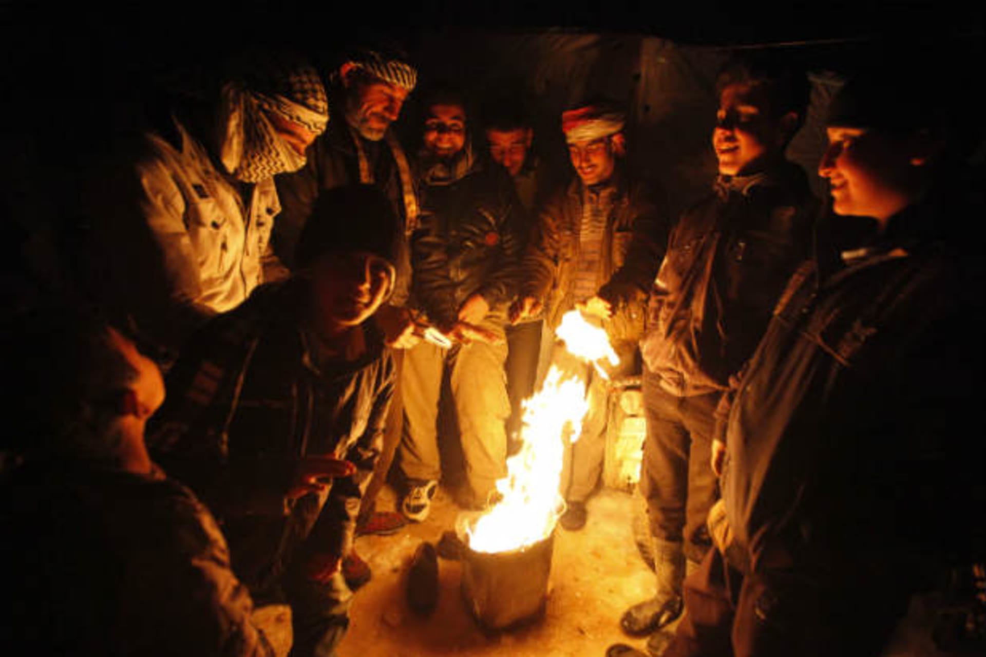 Syrian refugees from the town of Qara gather around a fire to keep themselves warm in a Syrian refugee camp on the Lebanese border town of Arsal, in eastern Bekaa Valley December 12, 2013 (Haju/Courtesy Reuters).