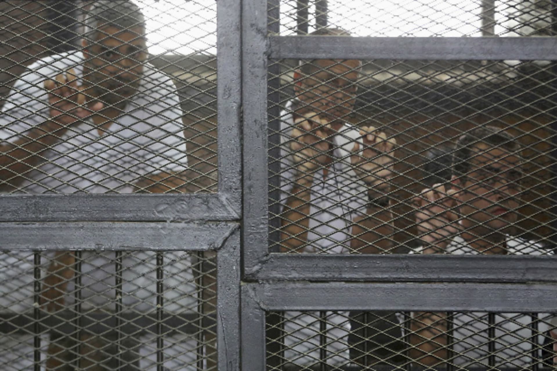 Al Jazeera journalists (L-R) Mohammed Fahmy, Peter Greste and Baher Mohamed stand behind bars at a court in Cairo May 15, 2014 (Courtesy Reuters).