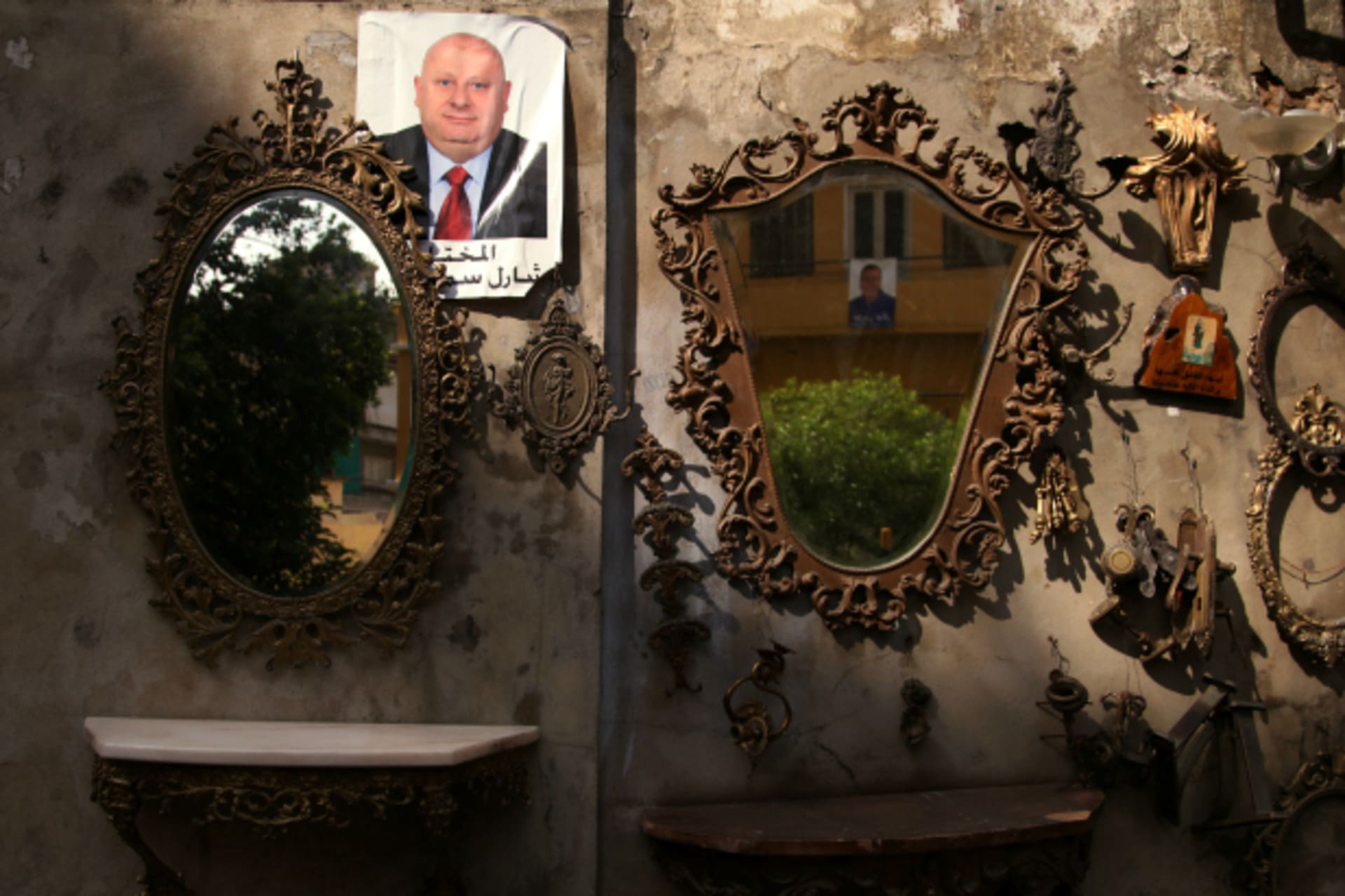 <p>A picture of a candidate for municipality elections is hung near displayed mirrors of an antique shop in Beirut, Lebanon (Alia Haju/Reuters).</p>
