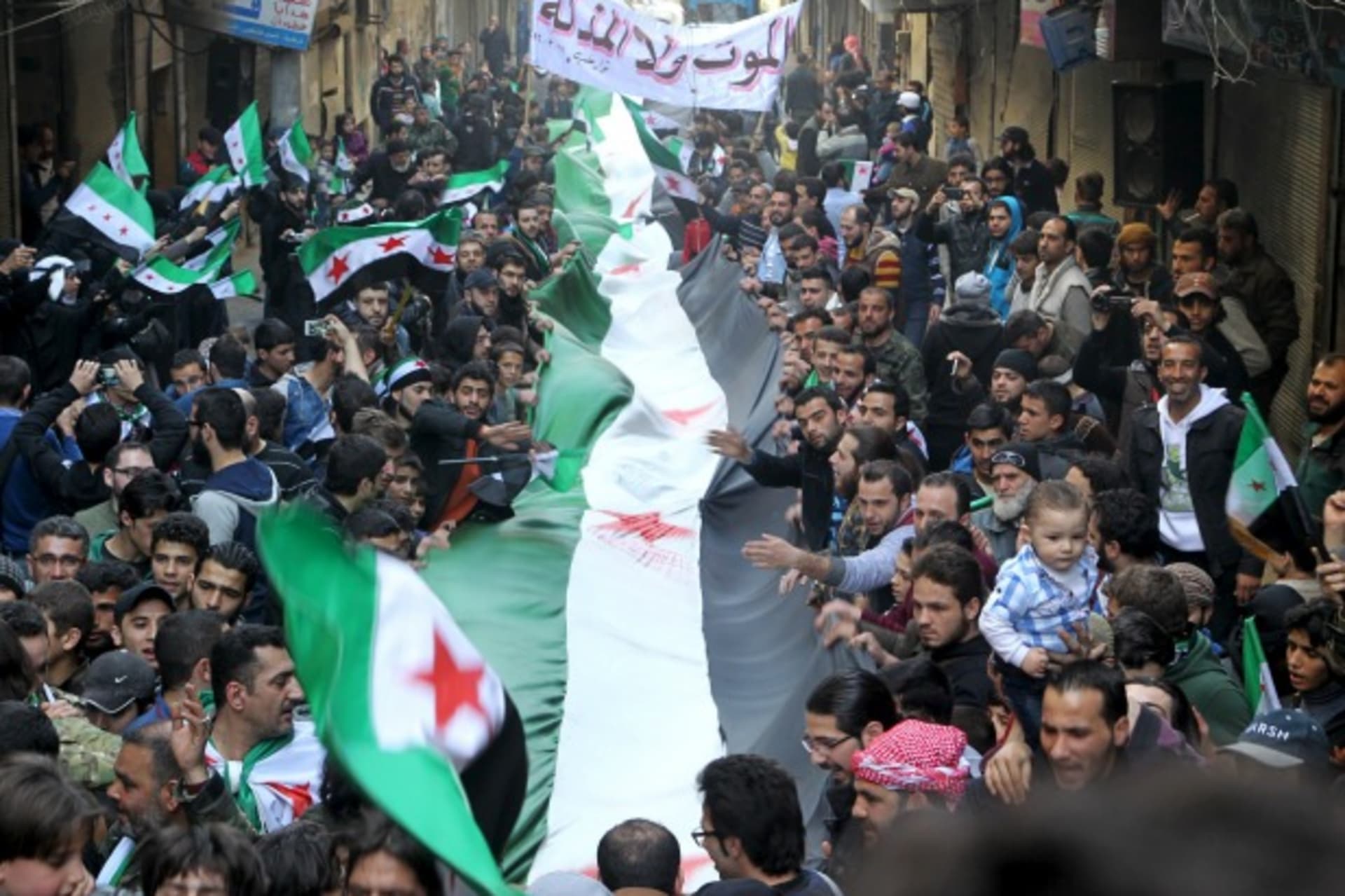 <p>Protesters carry a Free Syrian Army flags during an anti-government protest in the al-Sukari neighborhood of Aleppo, Syria (Abdalrhman Ismail/Reuters).</p>
