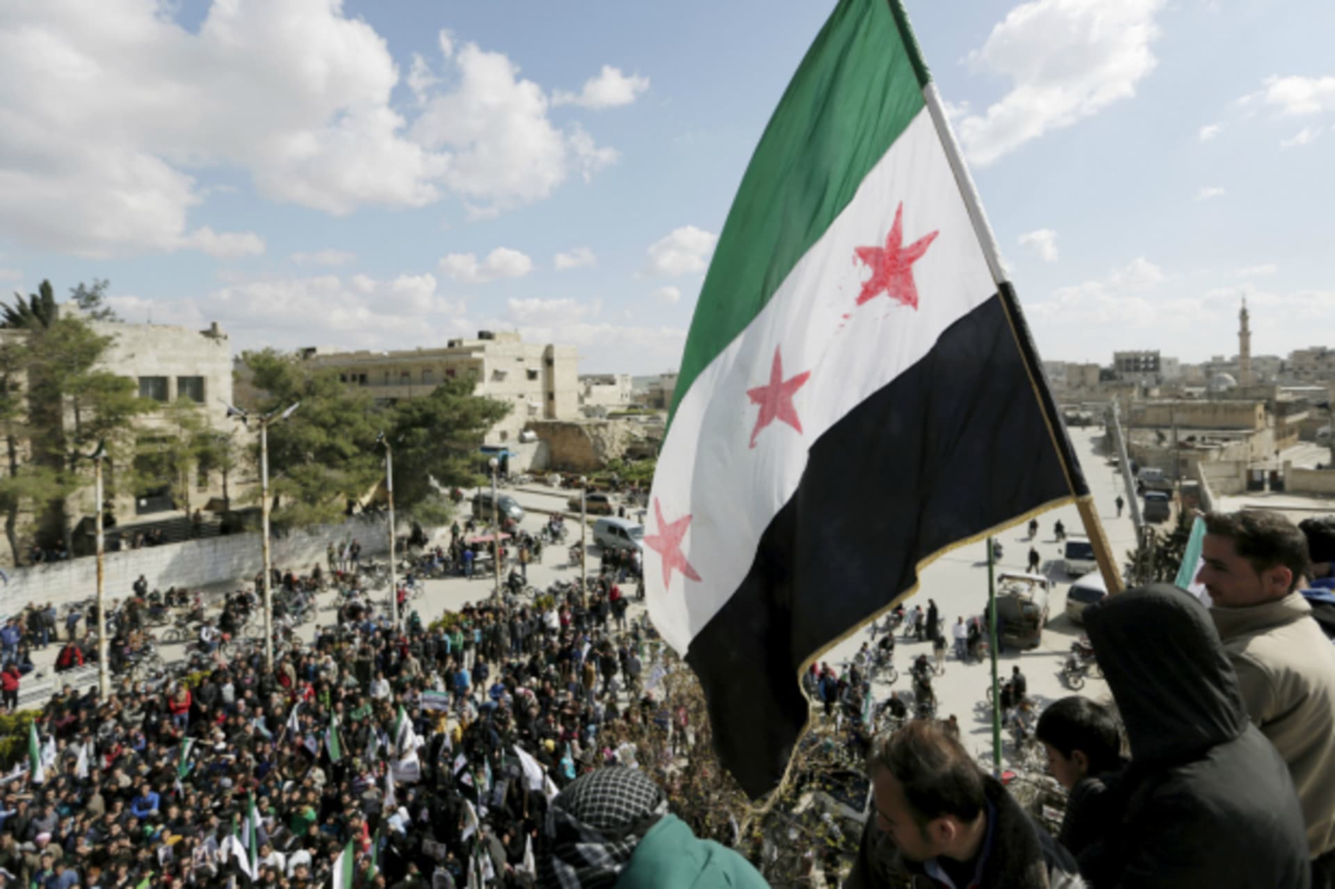 <p>Men carry a Free Syrian Army flag while attending an anti-government protest in Maarat al-Numan, south of Idlib, Syria (Khalil Ashawi/Reuters).</p>
