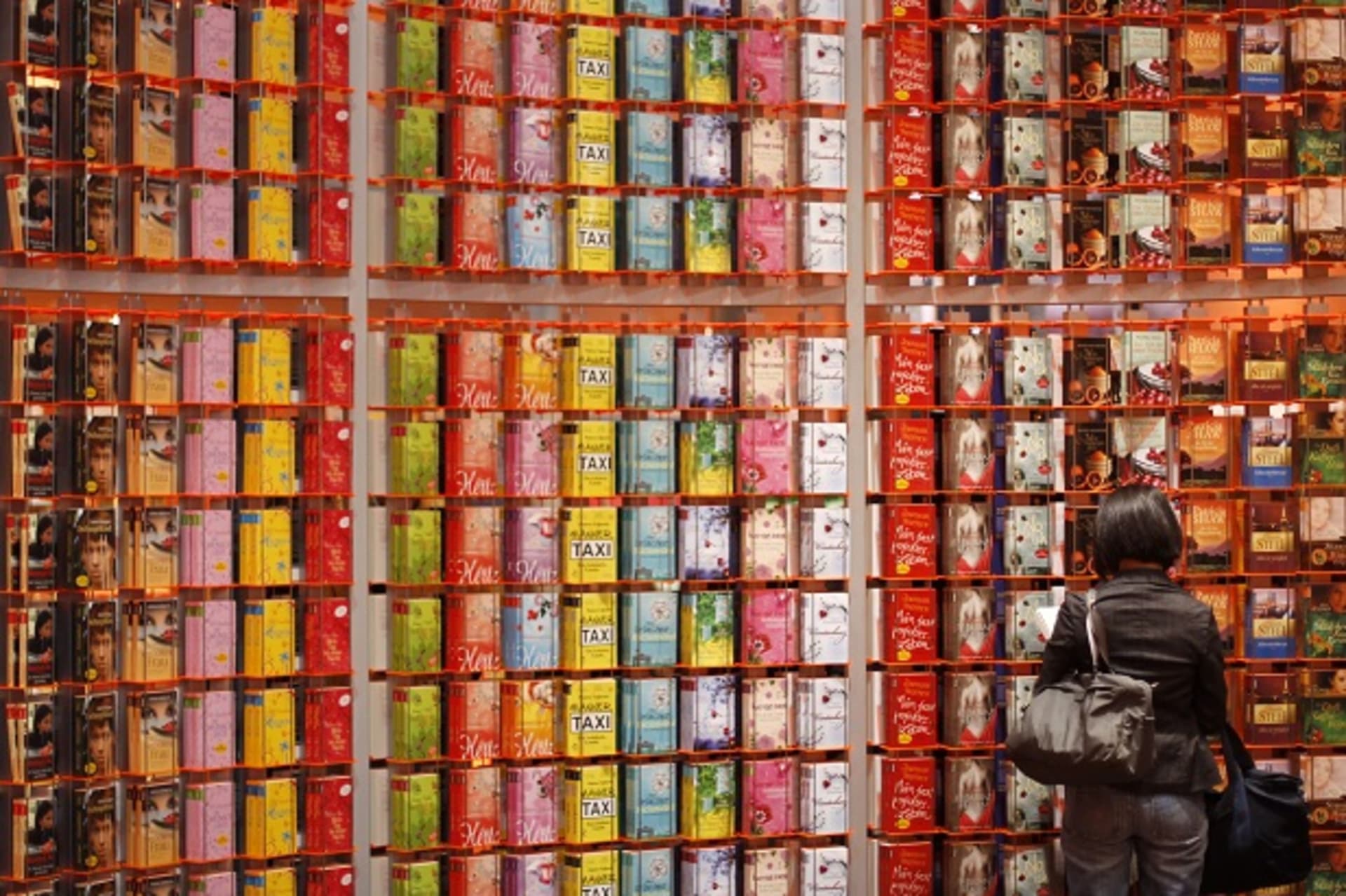 A visitor looks at a book while standing in front of a giant bookshelf at the book fair in Frankfurt