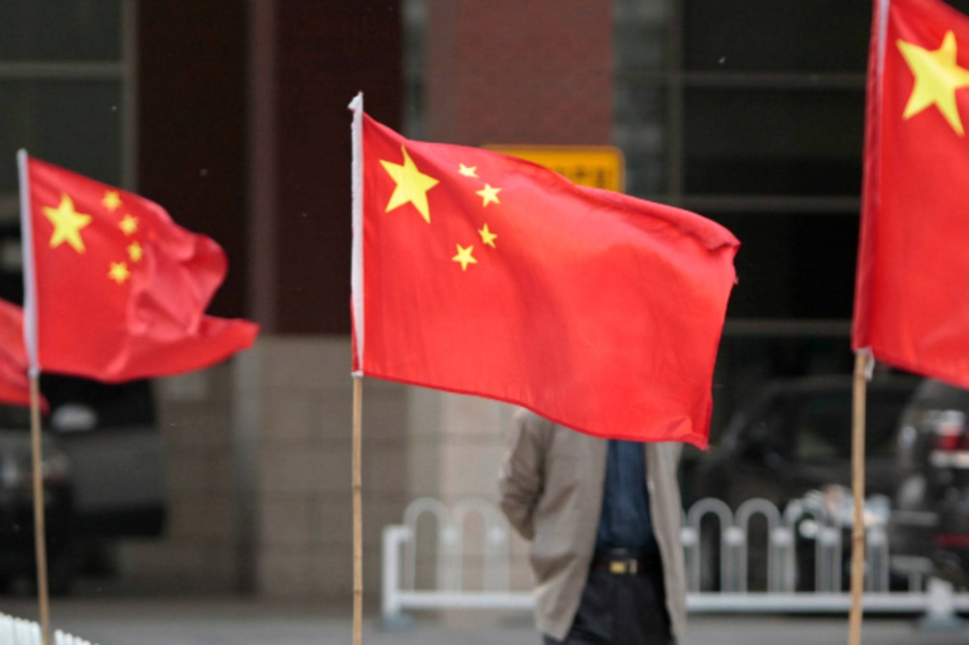 A man walks past Chinese national flags tied to iron fences at Chaoyang Hospital.