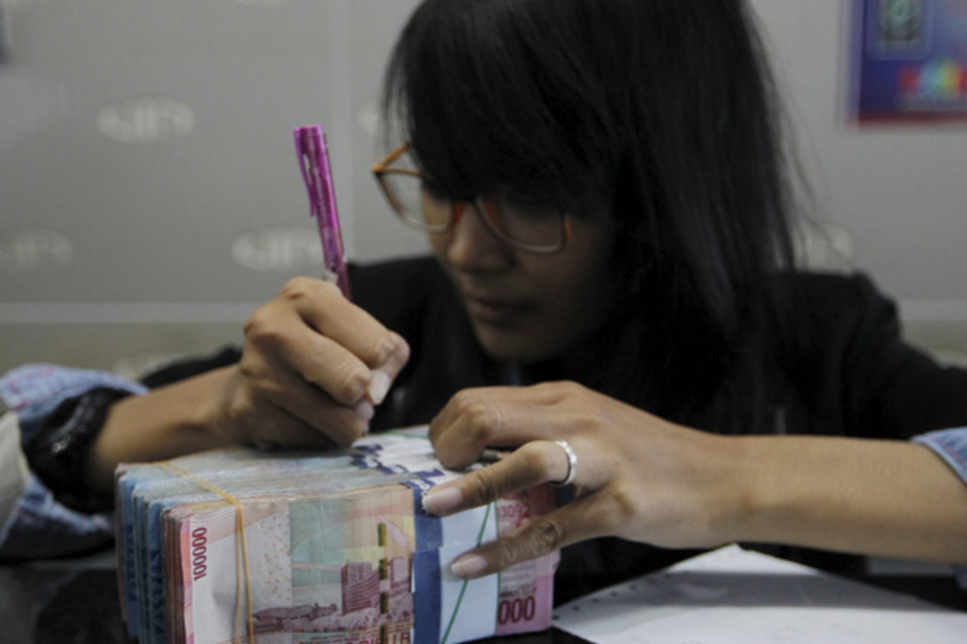 A money changer prepares Indonesian rupiah for a customer in Jakarta