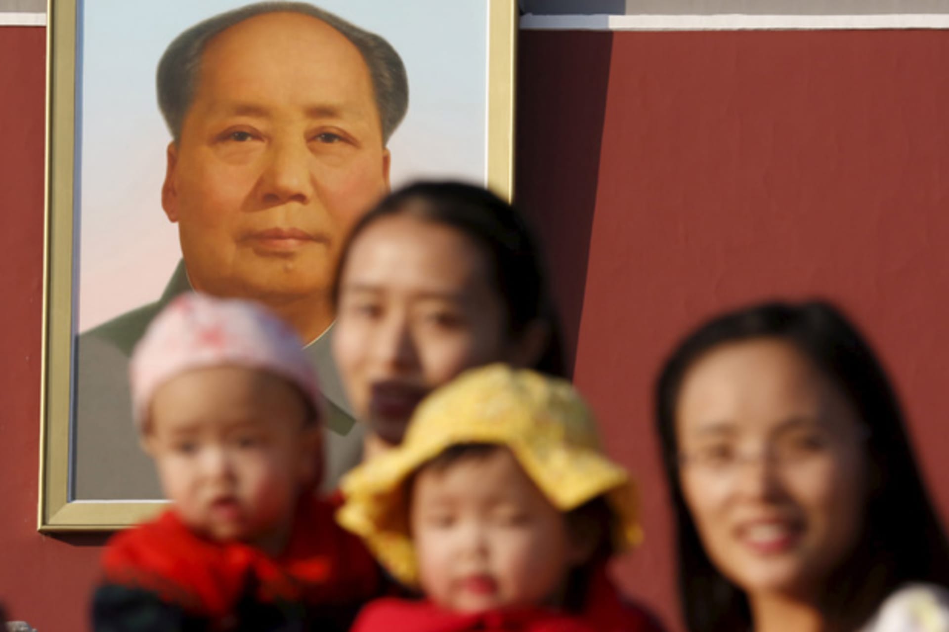 Two women and their babies pose for photographs in front of the giant portrait of late Chinese chairman Mao Zedong on the Tiananmen Gate in Beijing