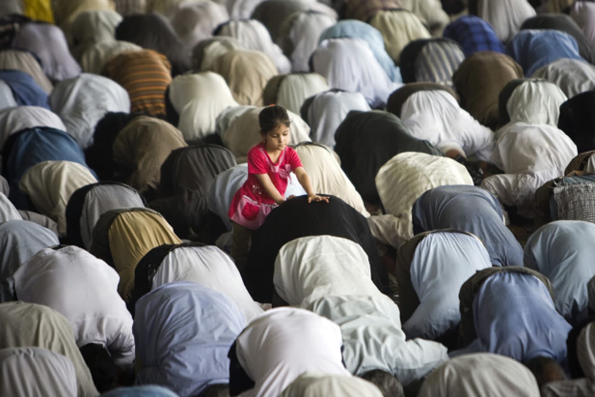 A girl plays with her father as he and fellow worshippers attend Friday prayers at Tehran University