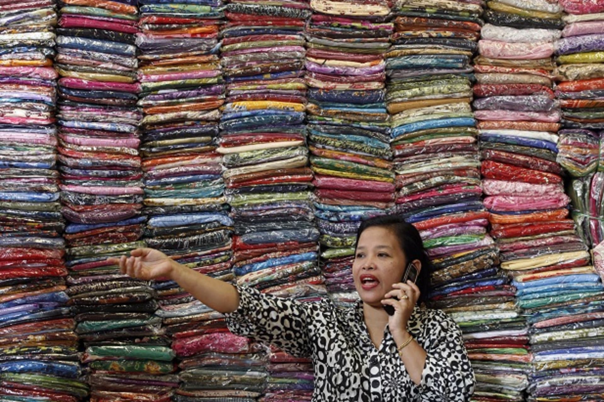 A businesswoman talks to a supplier as she sells cloth at her bazaar in Kuala Lumpur