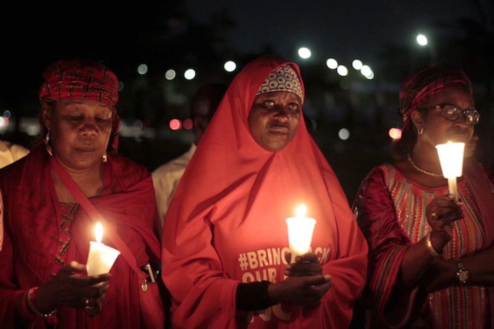 Bring Back Our Girls (BBOG) campaigners raise up candles during a candle light gathering marking the 500th day since the abduction of girls in Chibok, along a road in Abuja