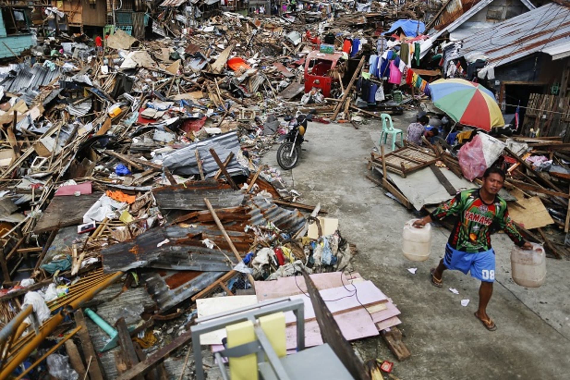 A survivor carries water cans as he searches for fresh water in an area devastated by Typhoon Haiyan in Tacloban