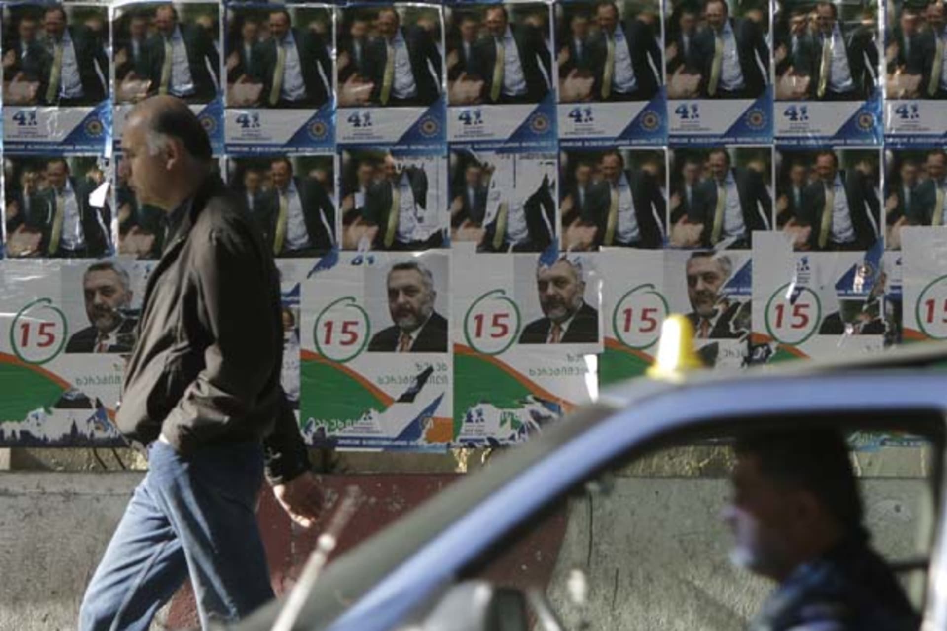<p>A man passes campaign posters in Tbilisi, Georgia (David Mdzinarishvili/Courtesy Reuters).</p>
