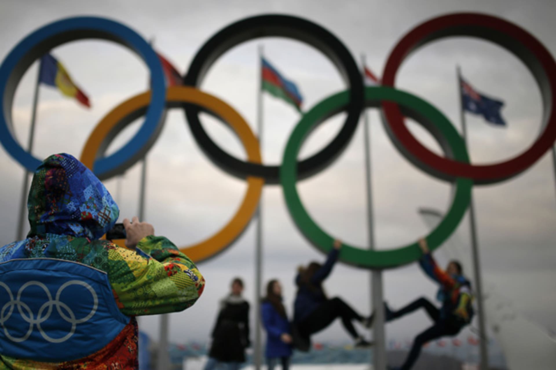 <p>An Olympic volunteer takes pictures of people posing under the Olympic rings in Sochi. (Phil Noble/Courtesy Reuters).</p>
