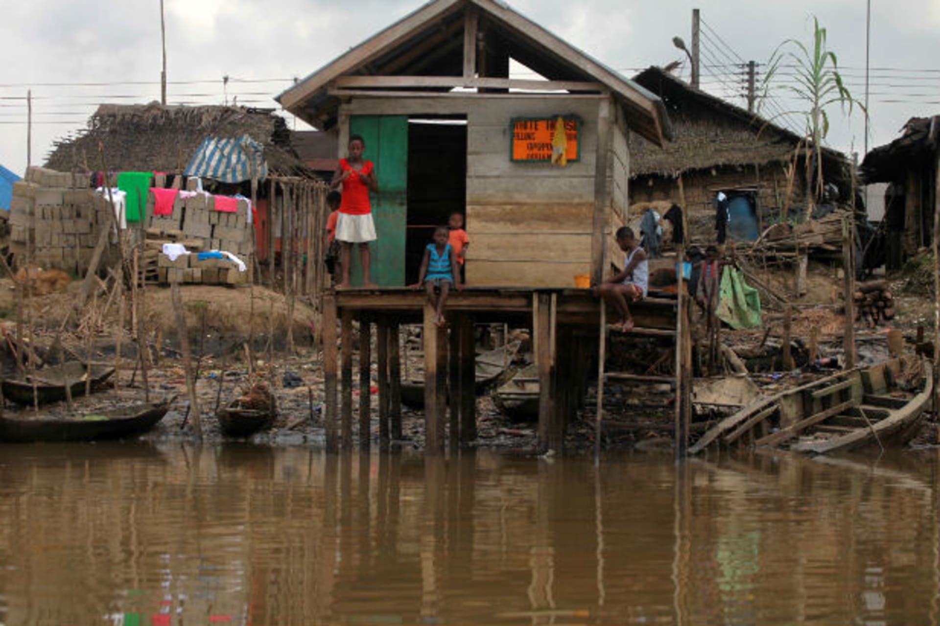 Children stand in front of a stilt house used as a local fuel station near river Nun in Nigeria's oil state of Bayelsa November 27, 2012.