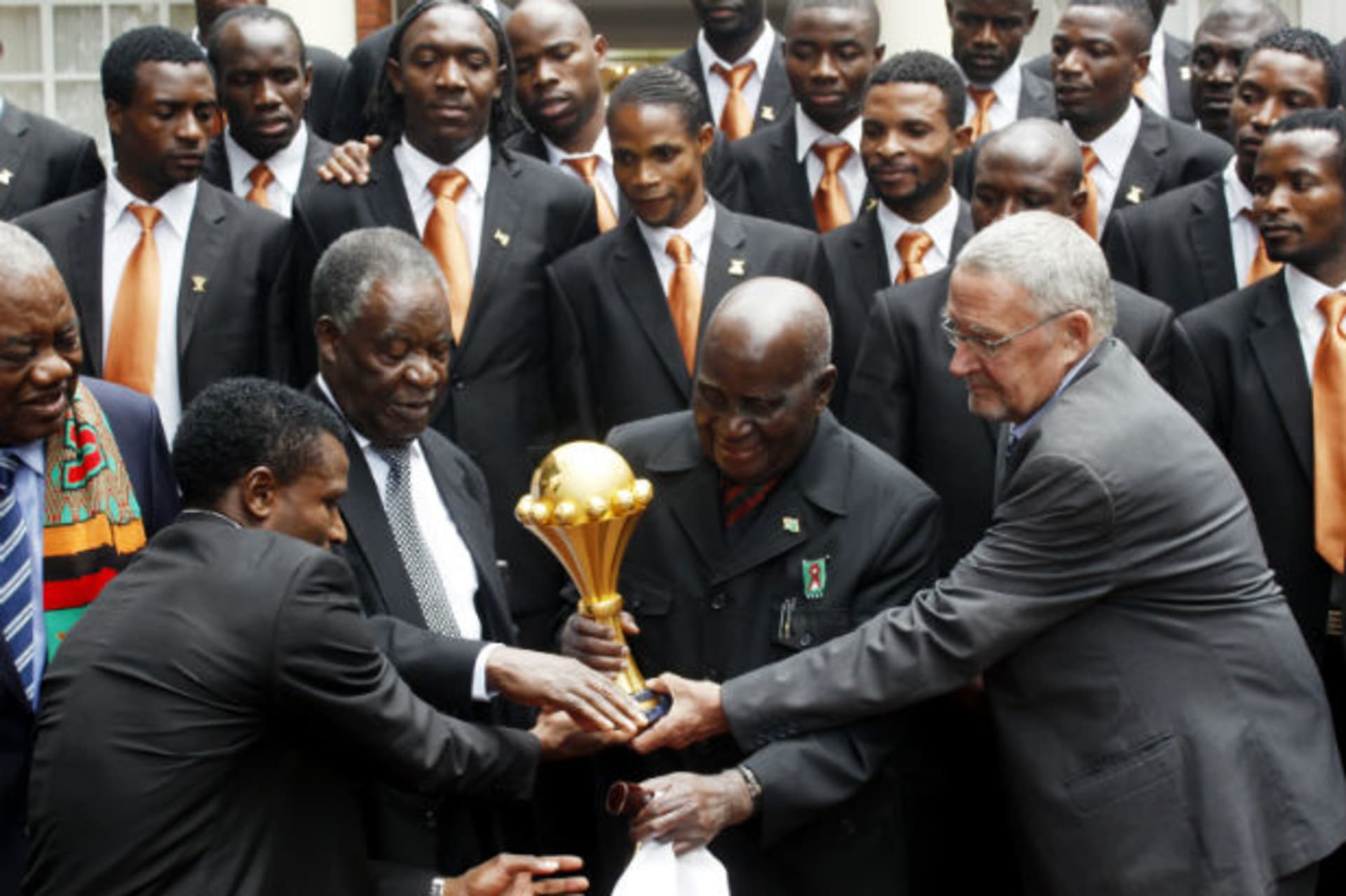 Zambia President Michael Chilufya Sata (3rd L) touches the African Nations Cup trophy with founding President Kenneth Kaunda (2nd R), Vice President Guy Scott (R) as members of the Zambia soccer team (back) and former President Rupiah Band (L)