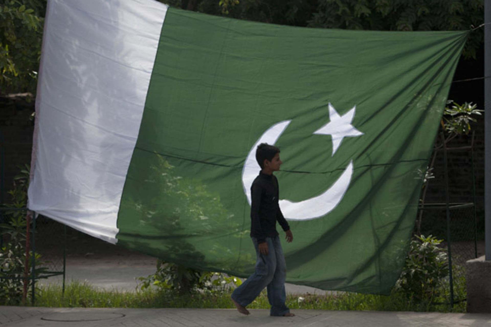 <p>A boy walks past a Pakistani flag in Rawalpindi (Faisal Mahmood/Courtesy Reuters).</p>