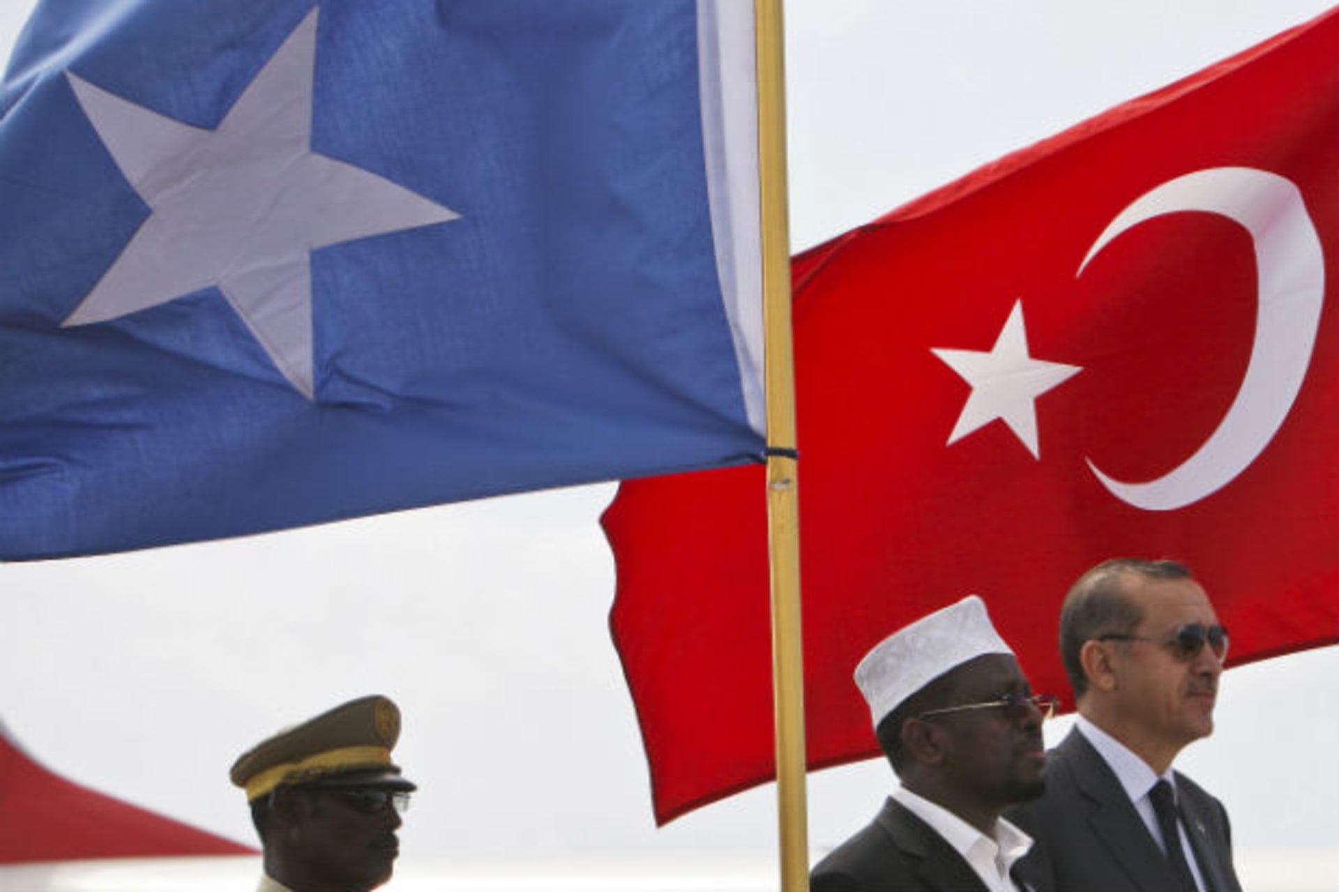 Turkey's PM Erdogan and Somalia's President Ahmed stand in front of their countries' national flags as they listen to the national anthems in Mogadishu 19/08/2011.