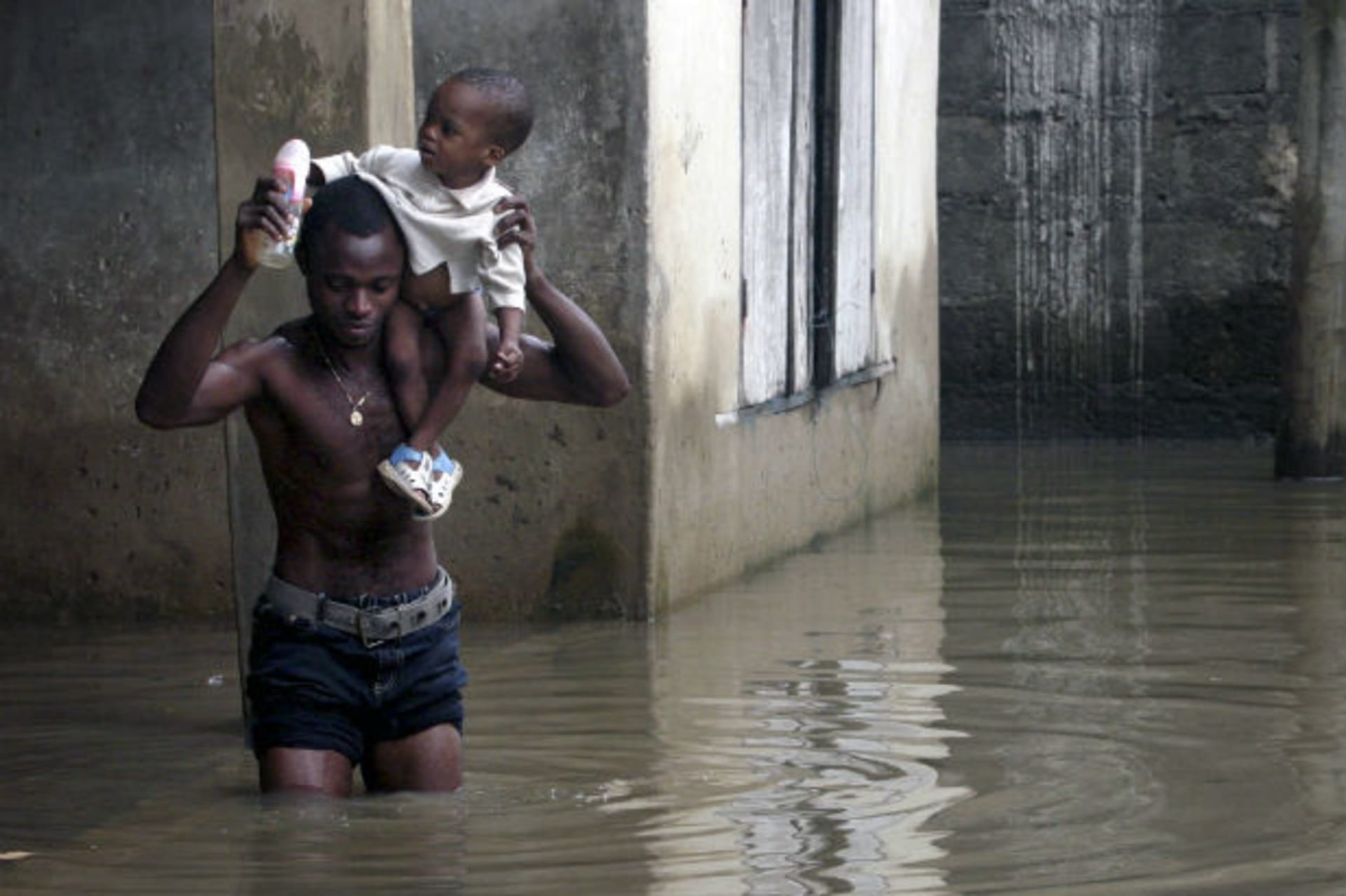 A man carries a child as he wades through flood waters in Ikorodu neighbourhood of Nigeria's main city of Lagos 05/08/2007.