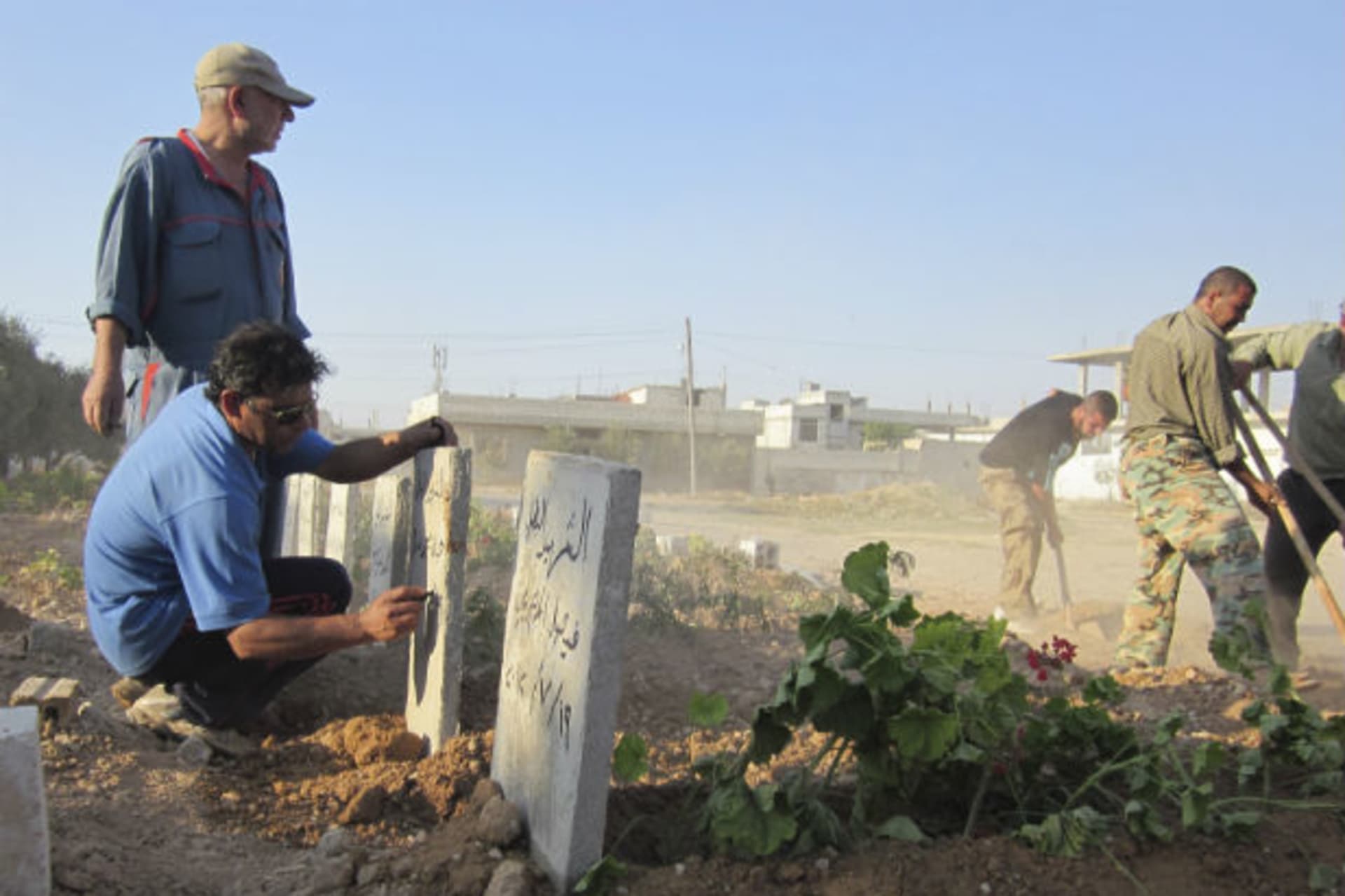 A man writes names on fresh graves of people whom activists say were killed by forces loyal to Syria's president Bashar al-Assad, after their funeral at the Qusseer neighbourhood of Homs on July 19, 2012 (Courtesy Reuters).