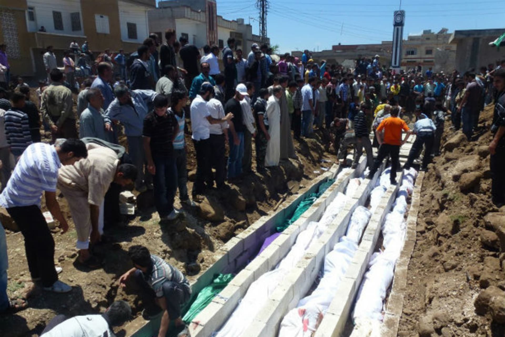 <p>People gather around a mass burial for victims purportedly killed at the massacre in the Syrian village of Houla on May 25. (Courtesy Reuters)</p>
