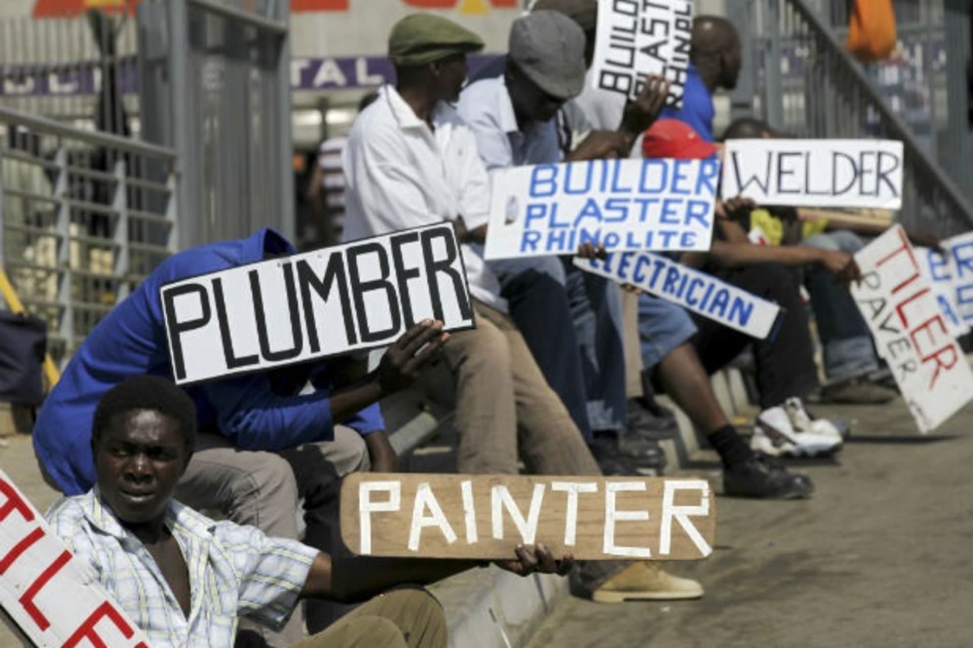 Men hold placards offering temporary employment services in Glenvista, south of Johannesburg, October 7, 2010.