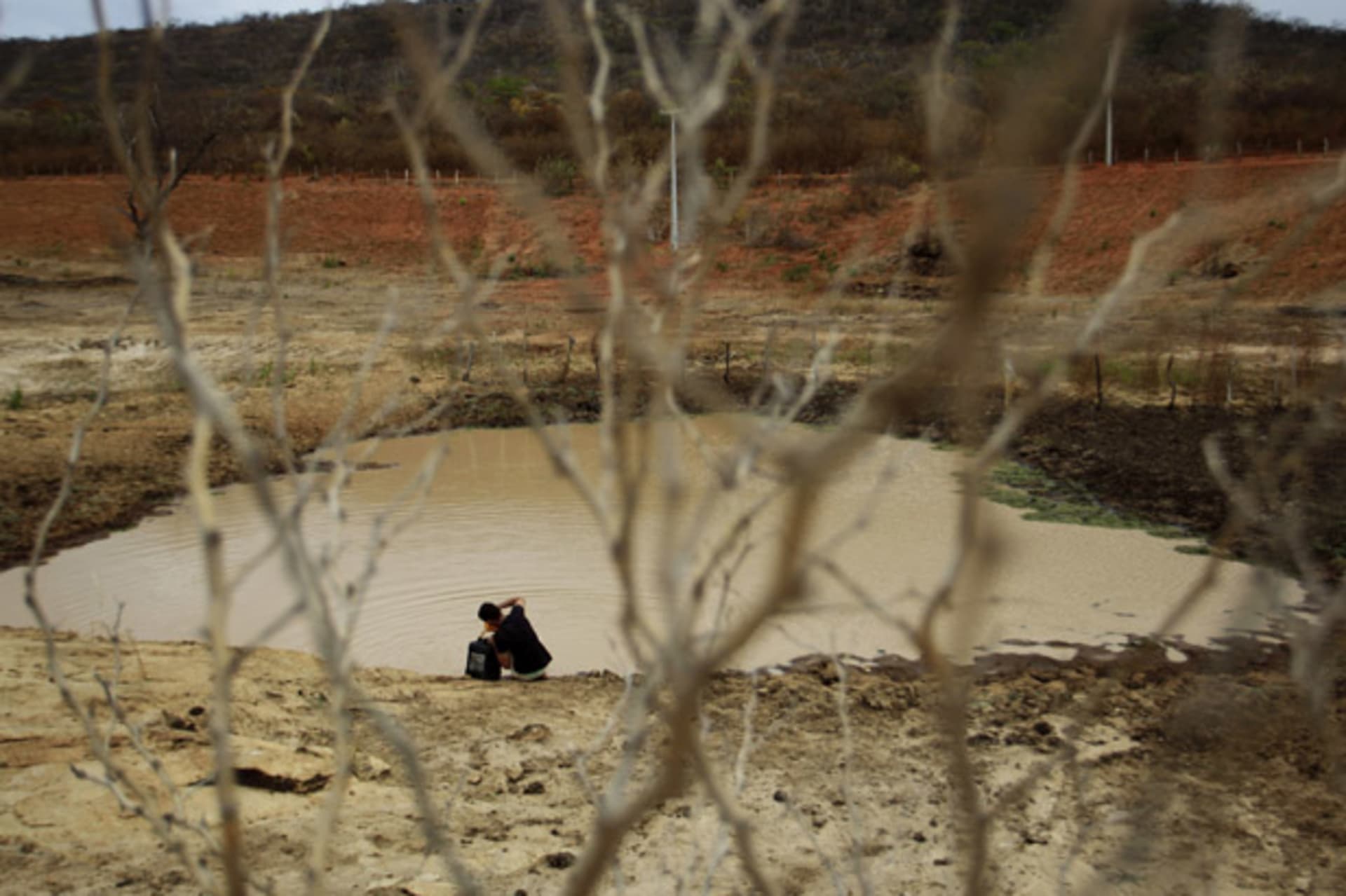Geovani Santos collects water from a weir which has nearly dried up as a consequence of the drought in Maracas