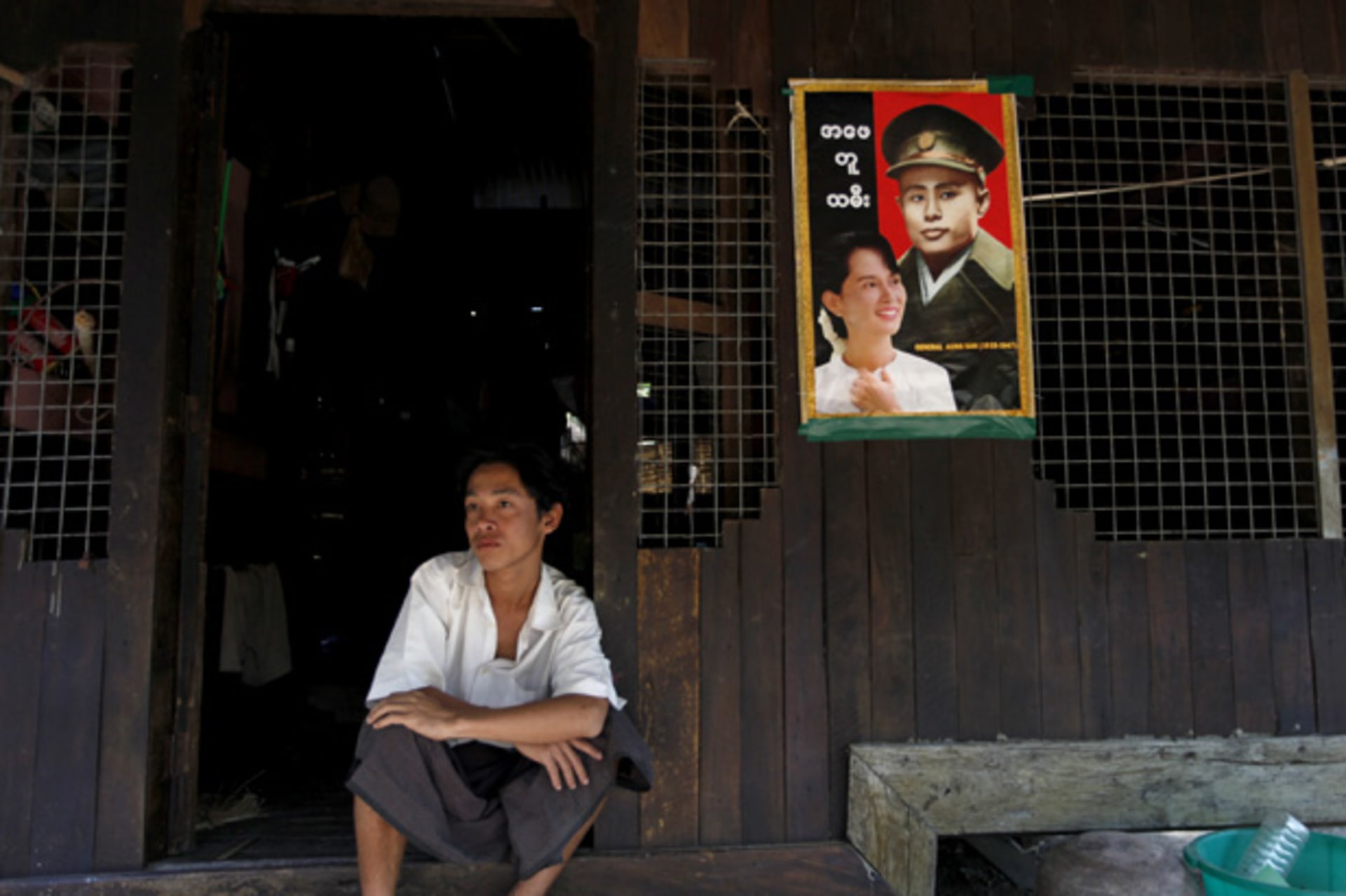 <p>A man sits in his home as pictures of Myanmar pro-democracy leader Aung San Suu Kyi and her father General Aung San hang on the wall in Phwartheinkha village.</p>

