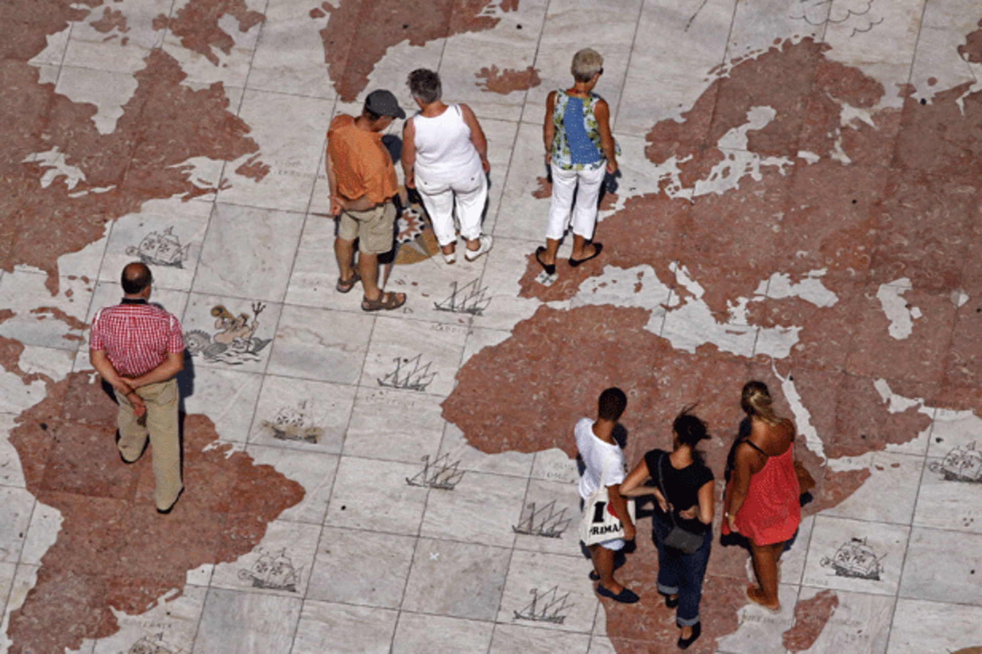 <p>People walk over a world map in Lisbon. (Jose Manuel Ribeiro/courtesy Reuters)</p>
