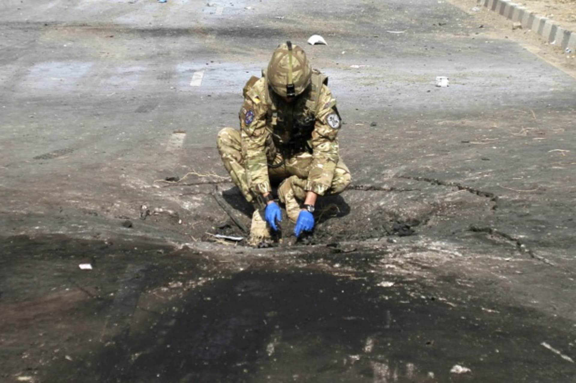 <p>A soldier investigates the crater caused by an explosion at the site of a suicide attack in Kabul, Afghanistan, in November 2011 (Courtesy Reuters/Mohammad Ismail).</p>
