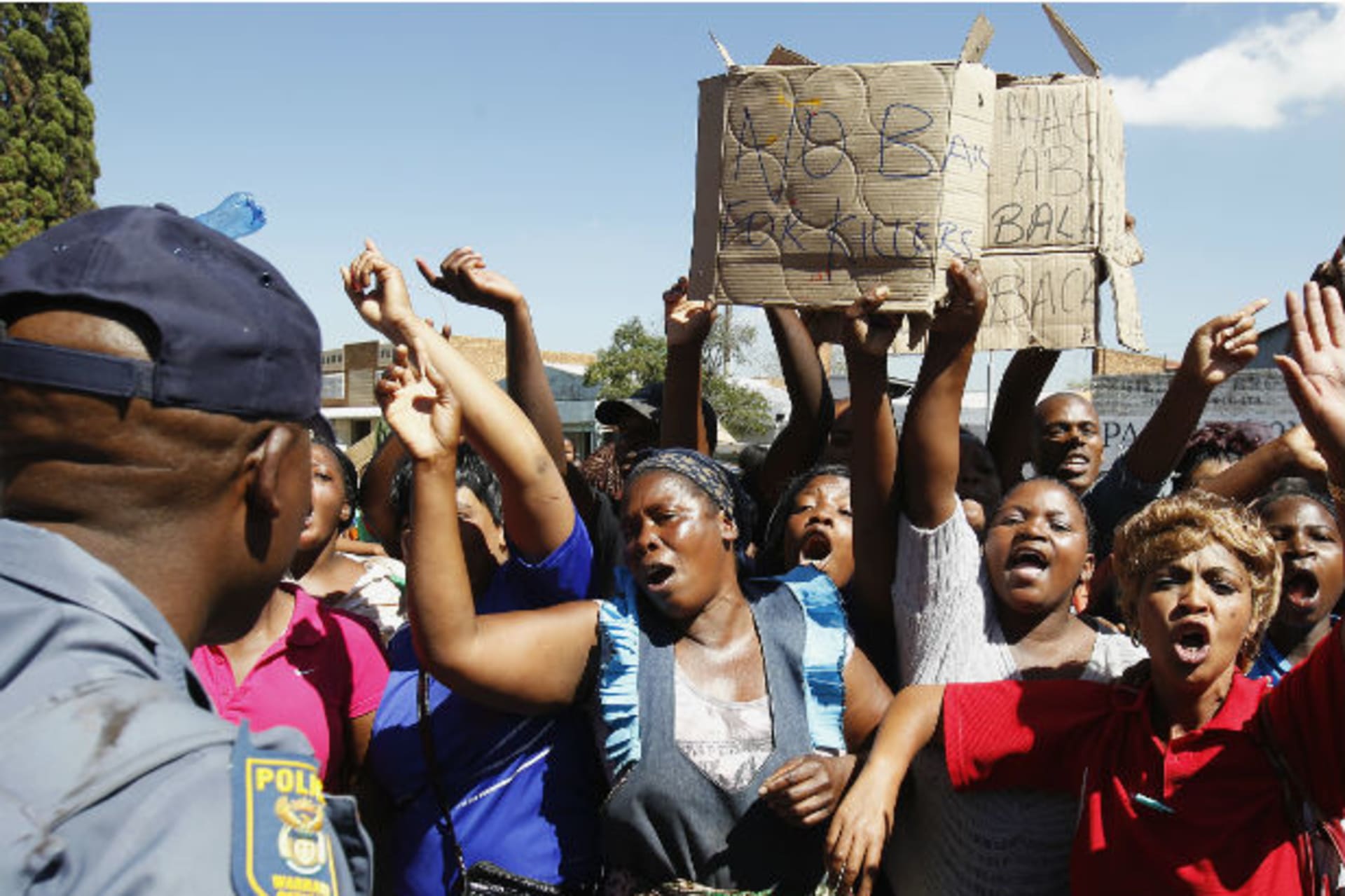 Protesters chant slogans in front of a policeman outside the Benoni courtroom, in east Johannesburg, March 4, 2013.