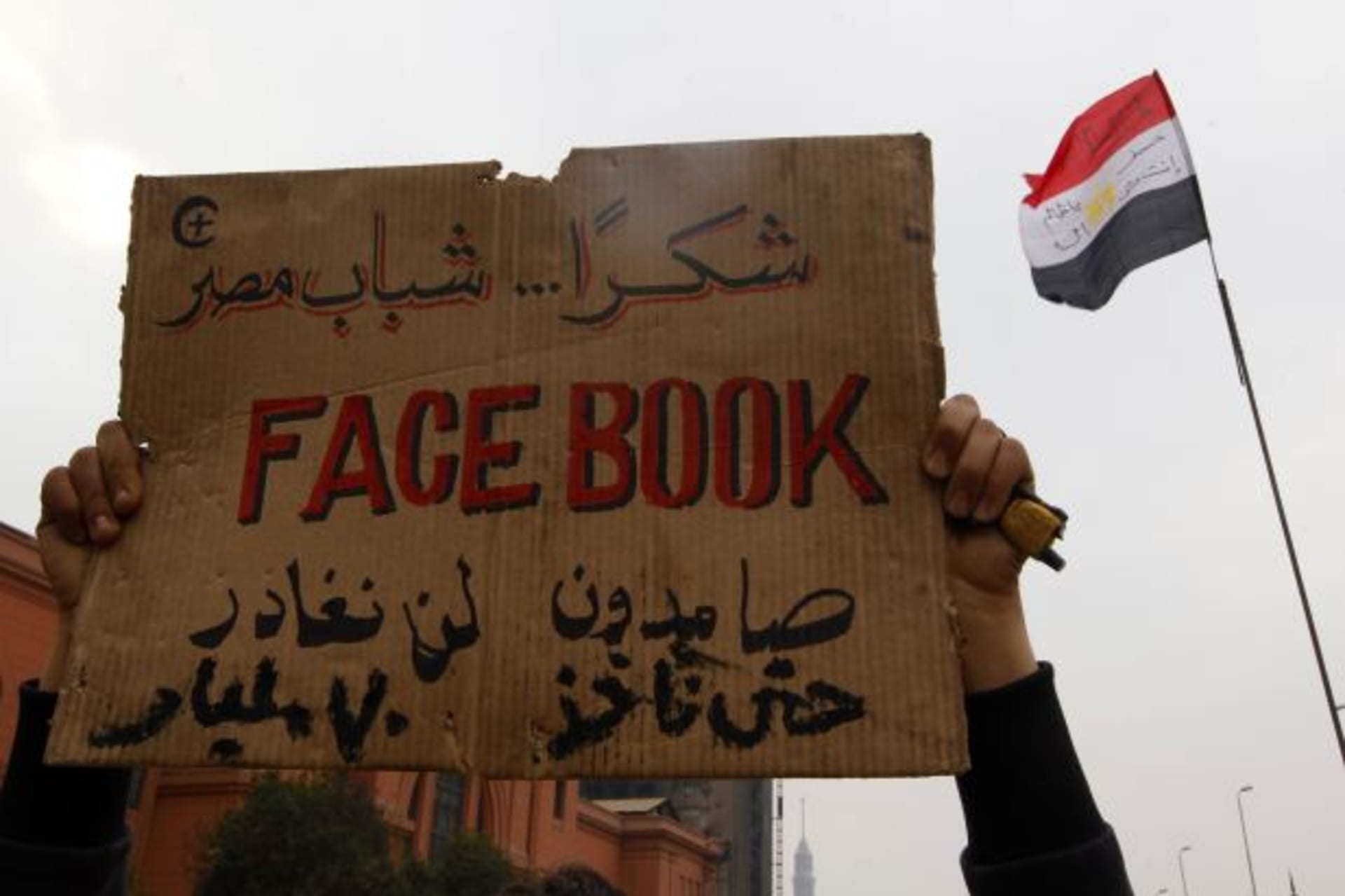 <p>An opposition supporter lifts a placard at the front line near Tahrir Square in Cairo, Egypt, in July 2011 (Yannis Behrakis/Courtesy Reuters).</p>
