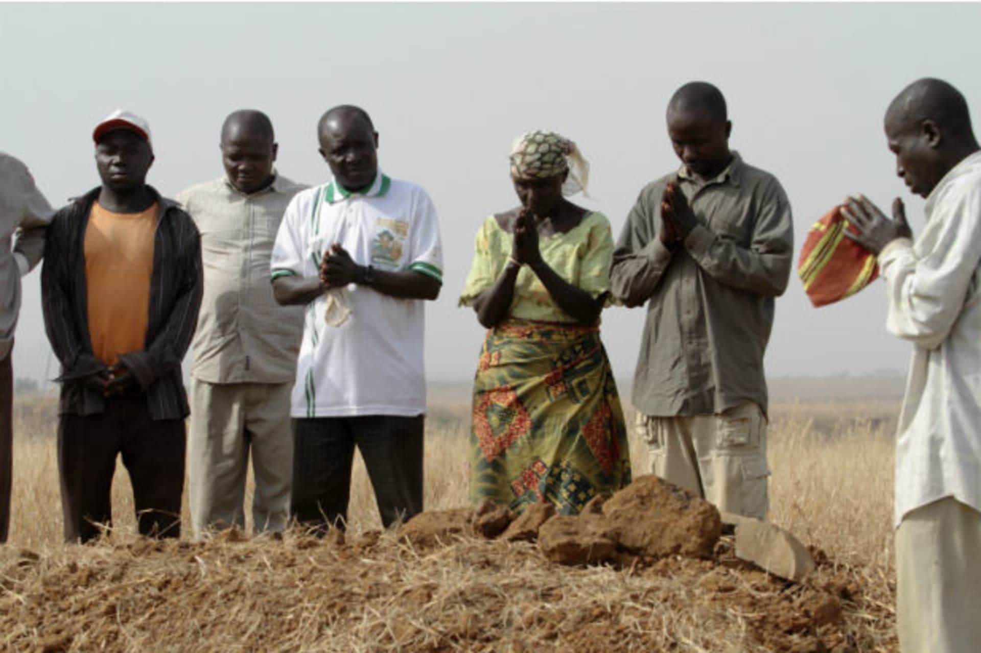 A family gathers around the grave, where three murdered family members were buried together, in Jos in Nigeria's Plateau state, December 28, 2011.