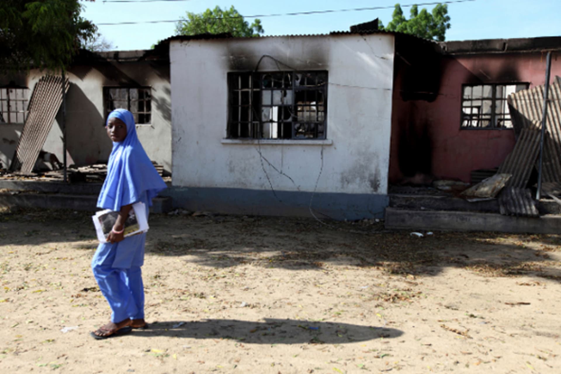 A school girl walks past a burnt building in the northern Nigerian city of Maiduguri, August 3, 2009.